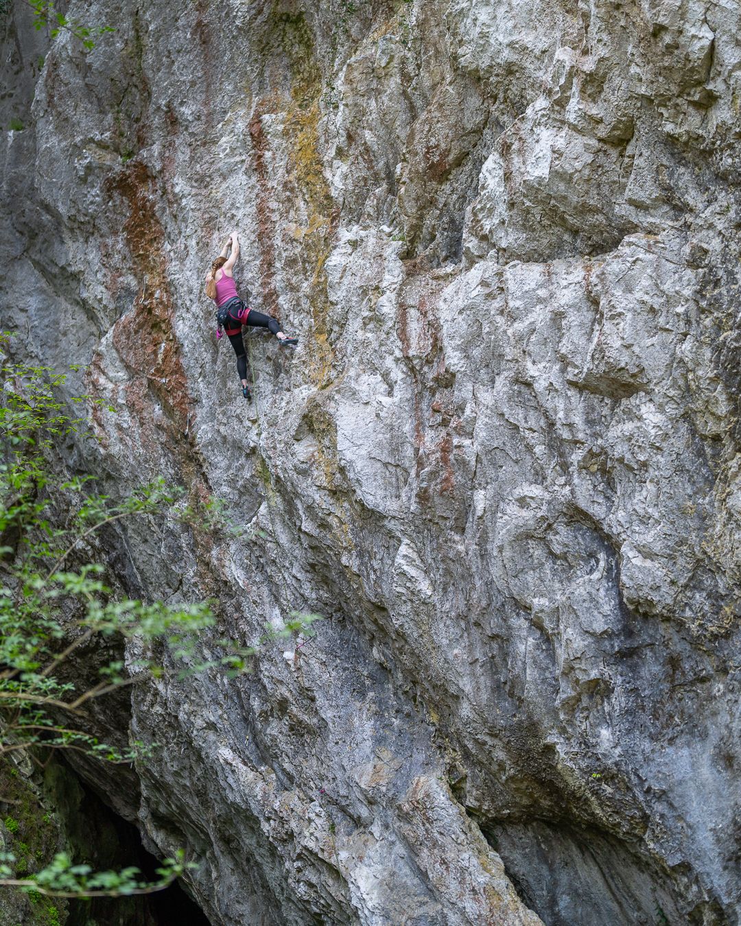 Climber ascending a challenging limestone rock face with precise technique and skill.