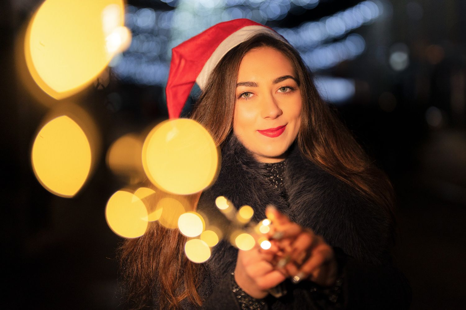 Artistic low-key portrait with warm golden bokeh lights in dark setting.