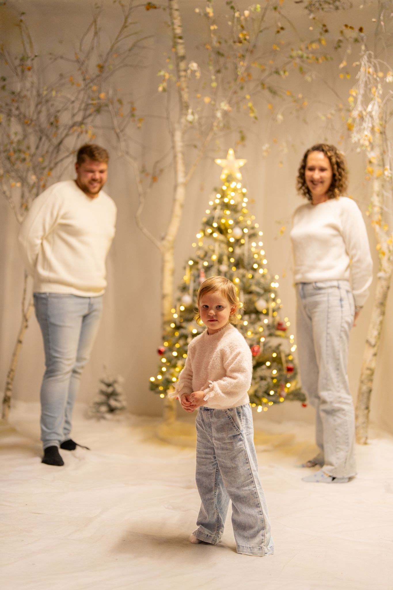 Holiday photo session with decorated Christmas trees and twinkling lights.