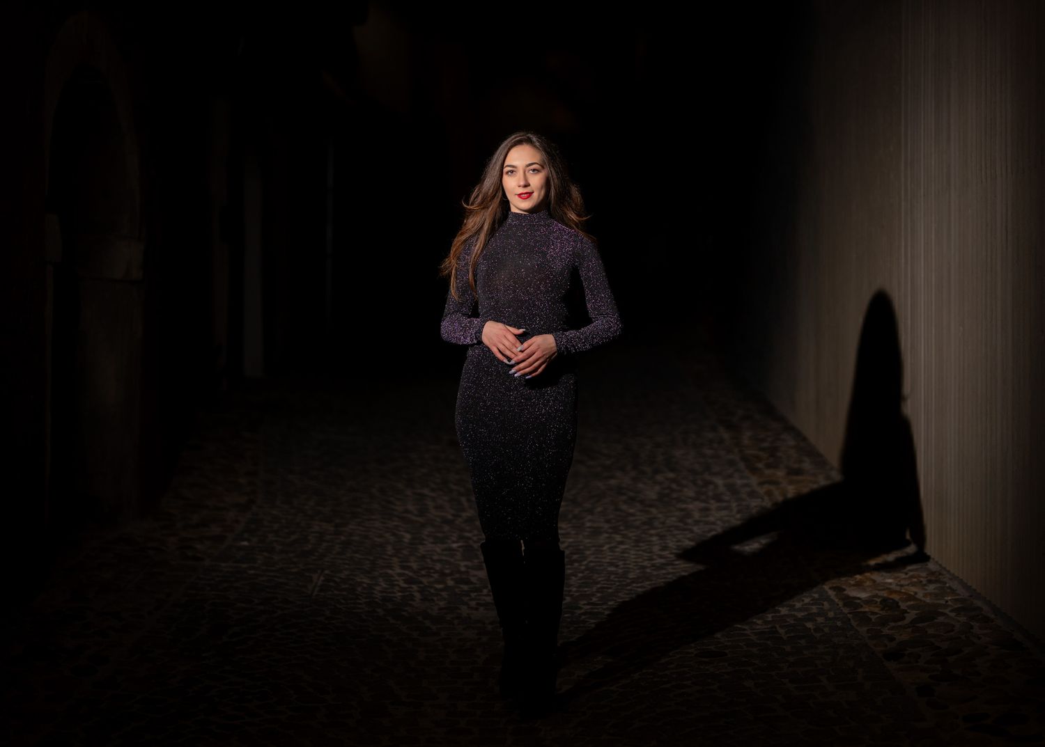 Dramatic portrait against dark background with glowing bokeh lights creating moody atmosphere.
