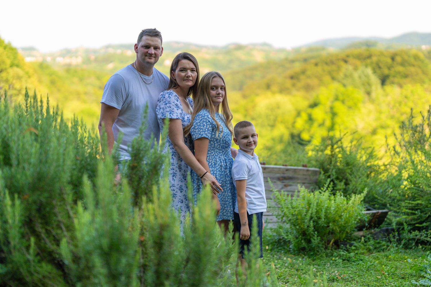 Družinsko fotografiranje v naravi. družina pozira na prostem v topli zlati svetlobi z zelenim ozadjem.