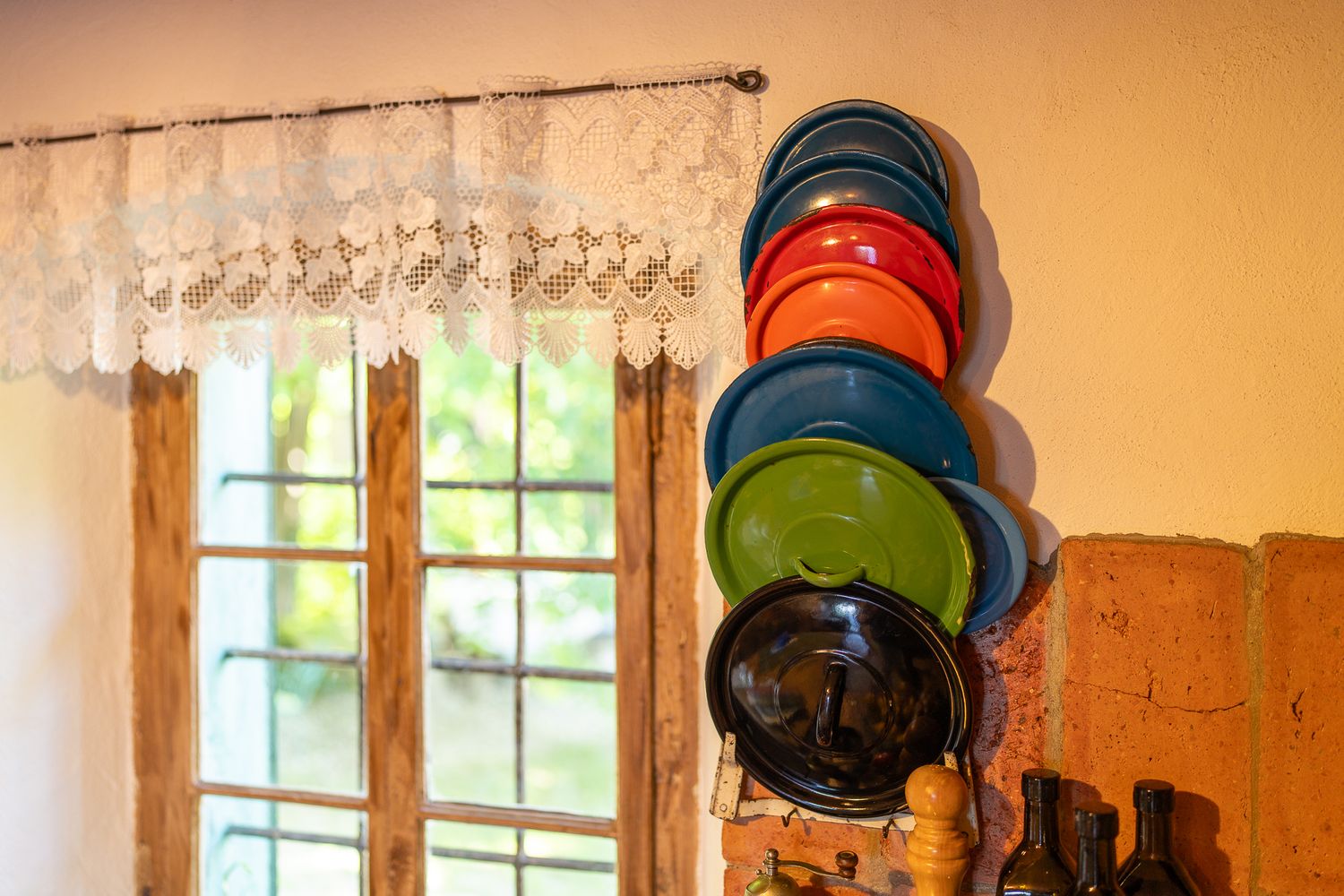 Kitchen wall display featuring colorful plates and cookware arranged on wooden shelving.