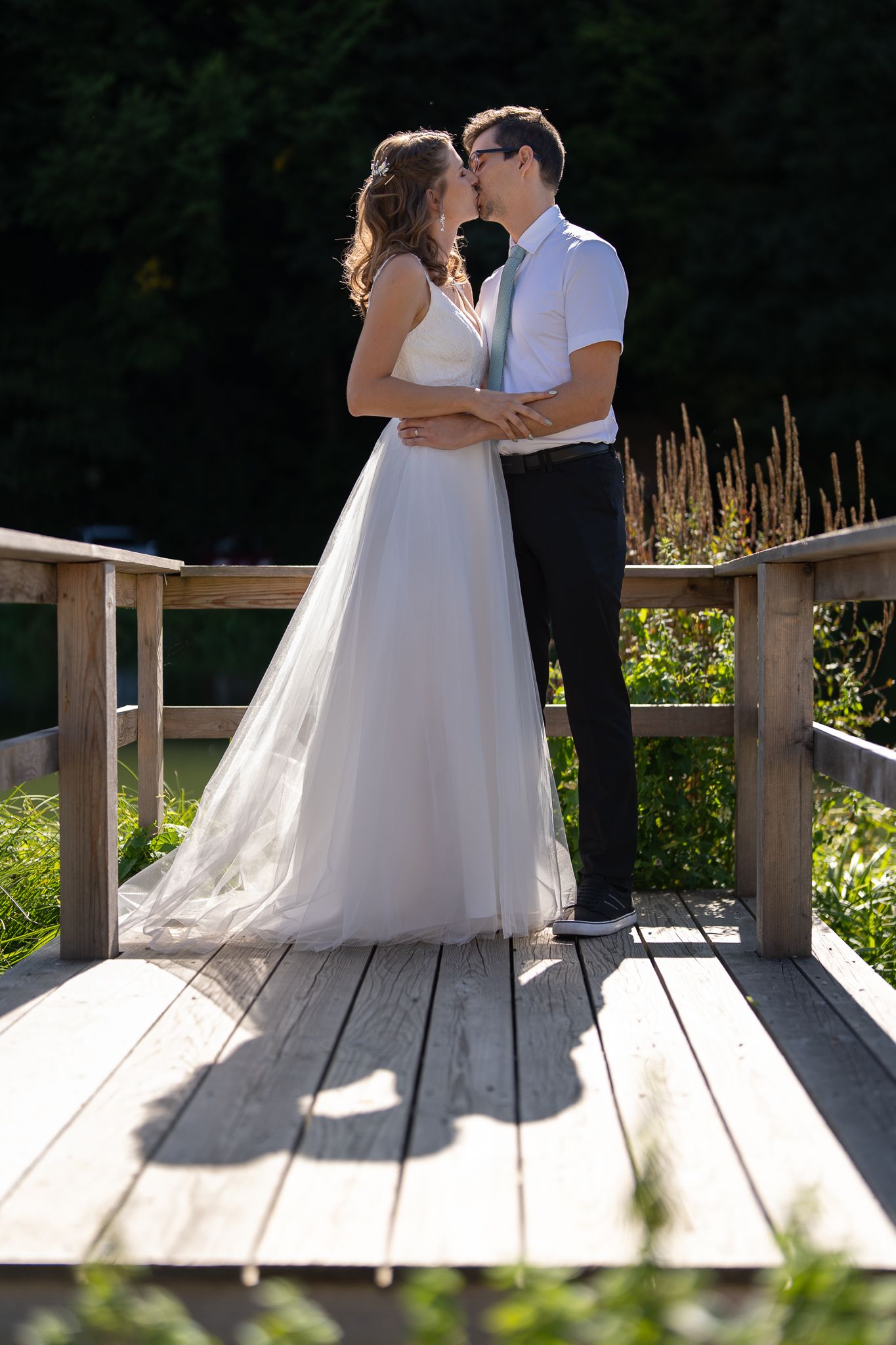 Romantic wedding photos taken on wooden deck with natural backdrop.