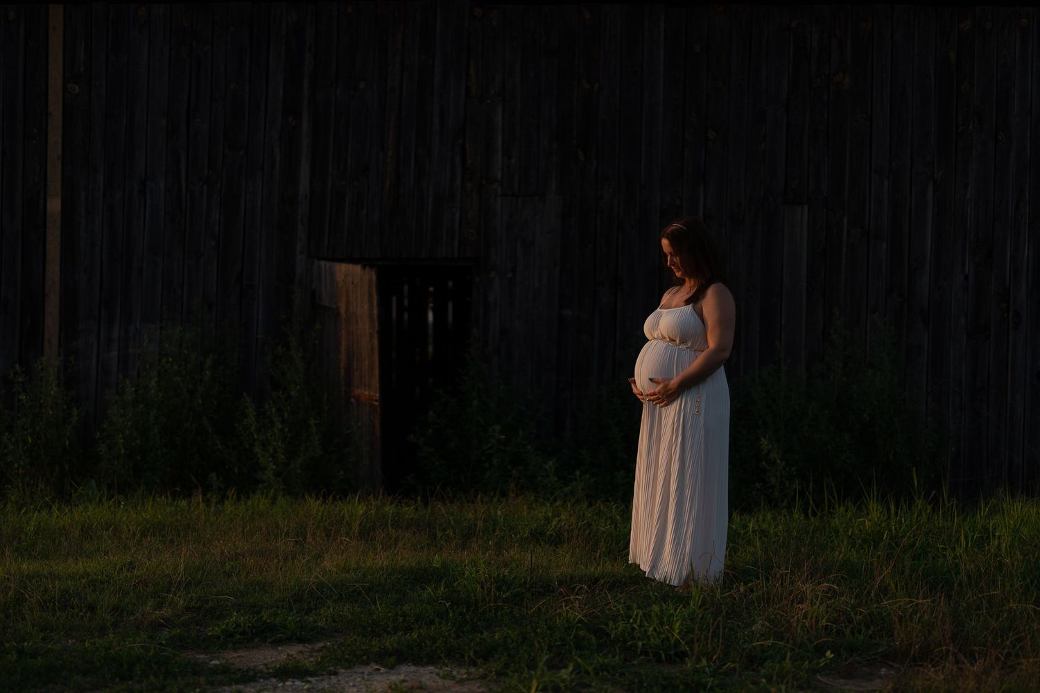 Ethereal maternity photography session at dusk with dramatic lighting and shadows.
