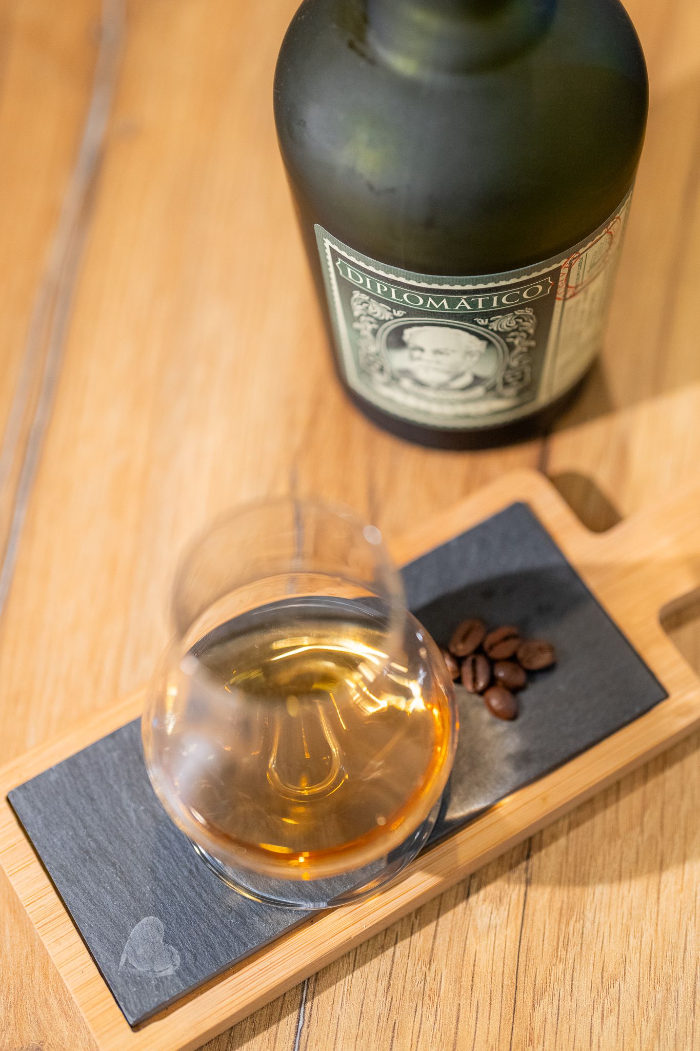 Golden whiskey served in tasting glasses on slate coasters against wooden background.