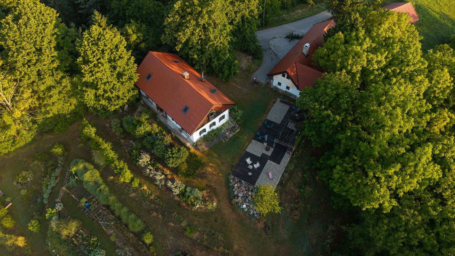 Aerial view of red-roofed buildings nestled among lush green trees in a rural setting.