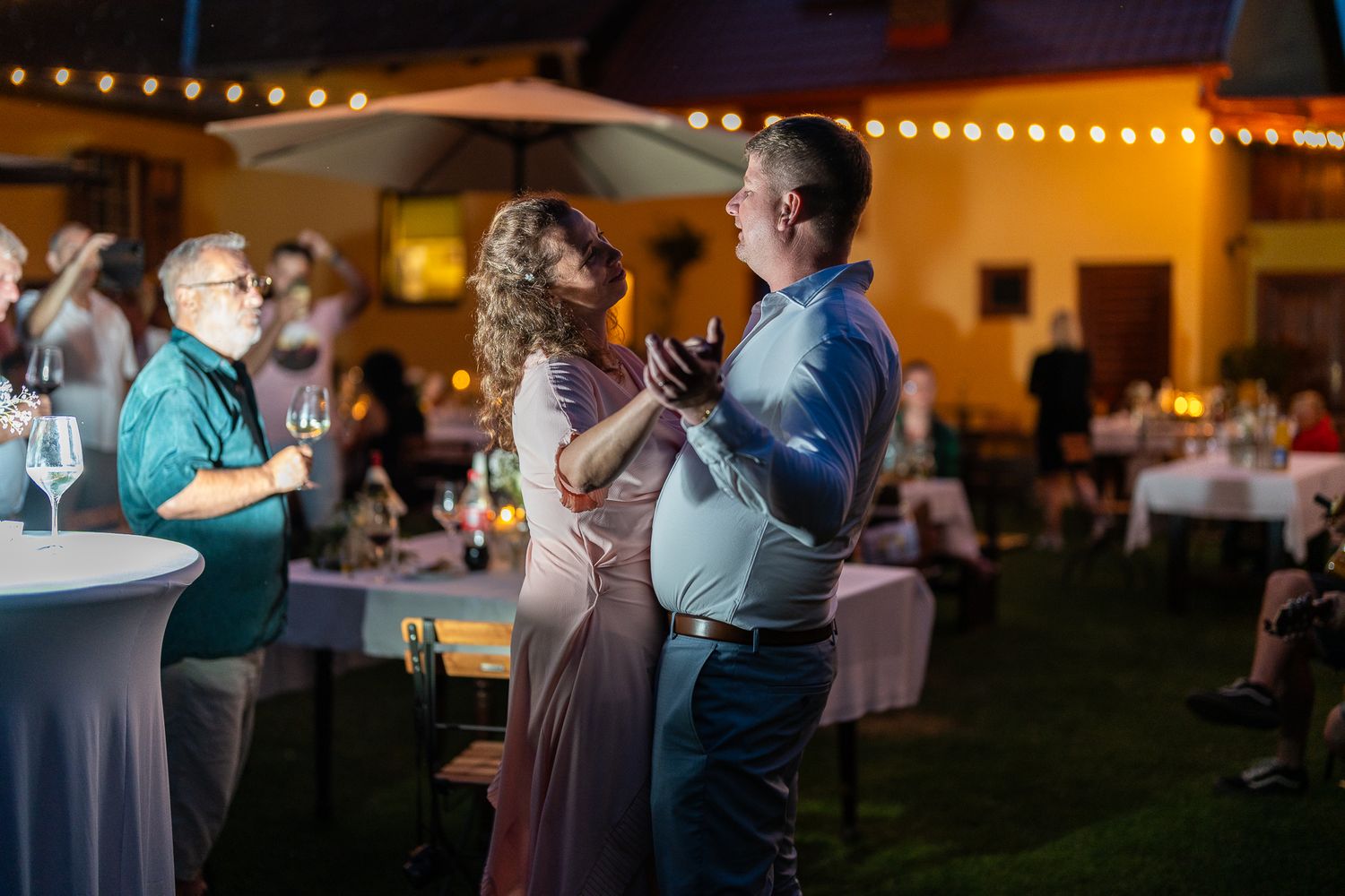 Couples dance together at an outdoor evening reception with string lights creating a romantic atmosphere.