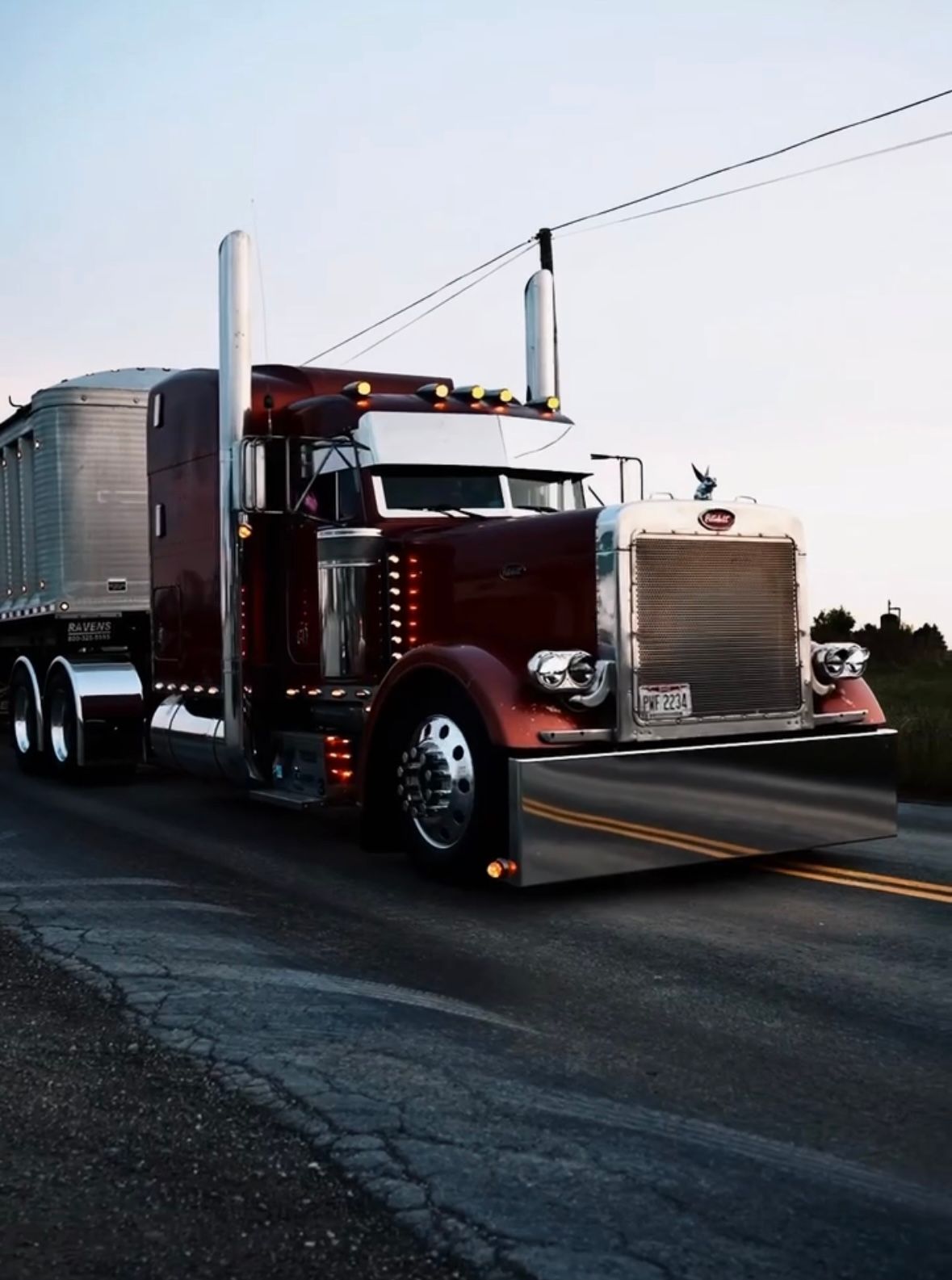 A burnt orange Peterbilt semi truck with a dump trailer