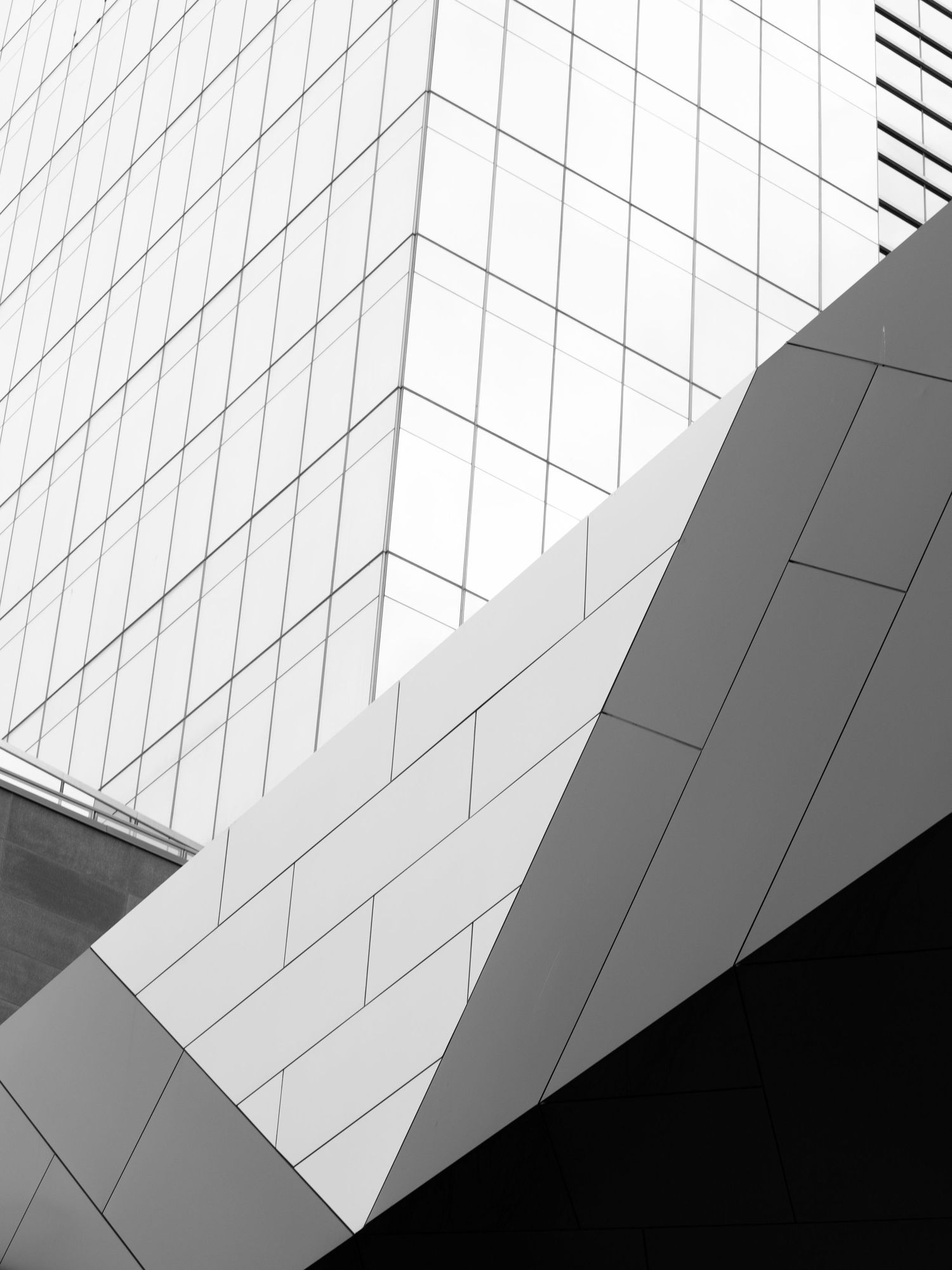 Abstract black and white architectural detail of a modern building showing angular geometric tile panels and sharp lines.