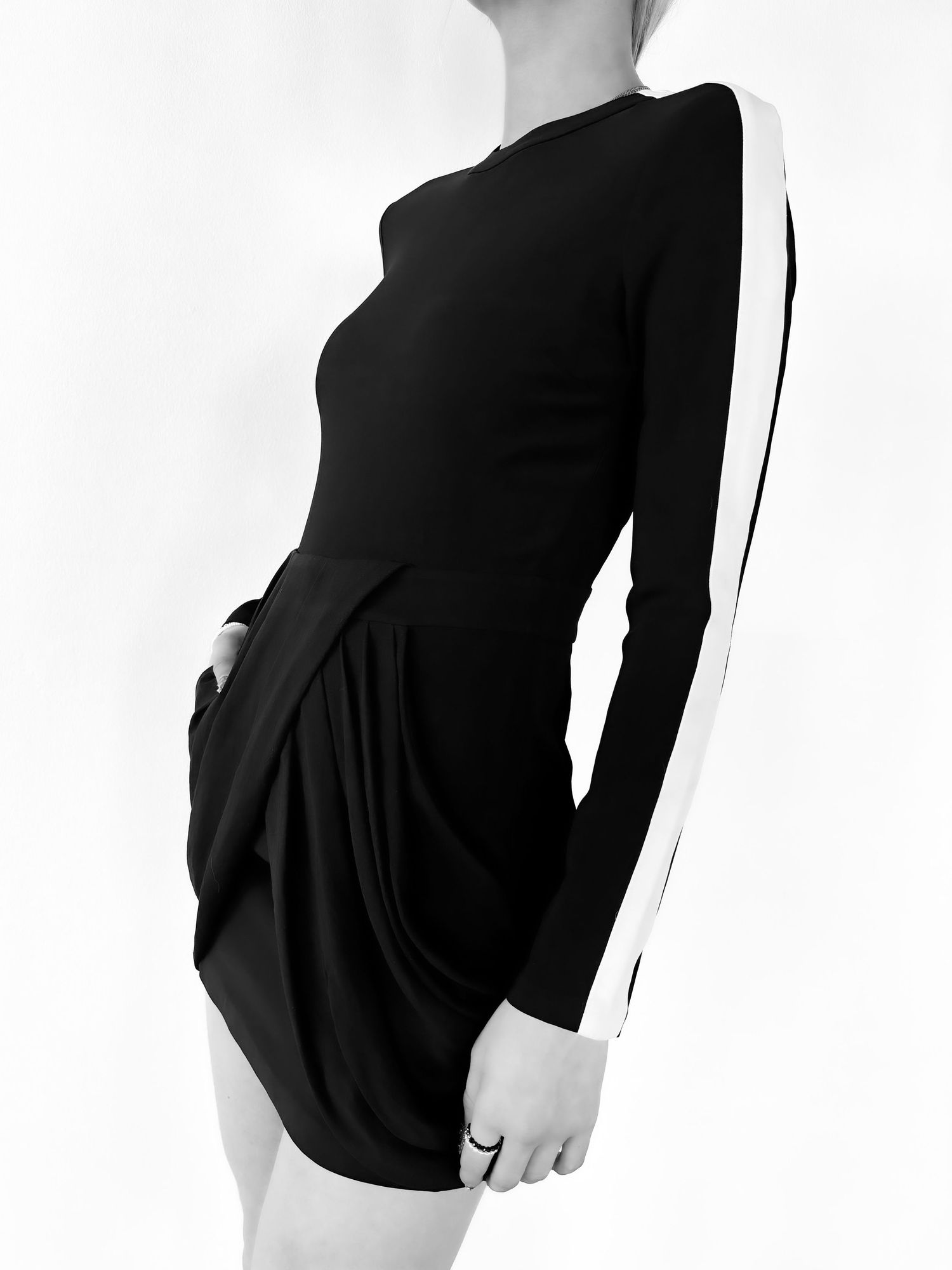 Black mini dress with white side stripes and long sleeves, featuring draped skirt detail, worn by a female model.
