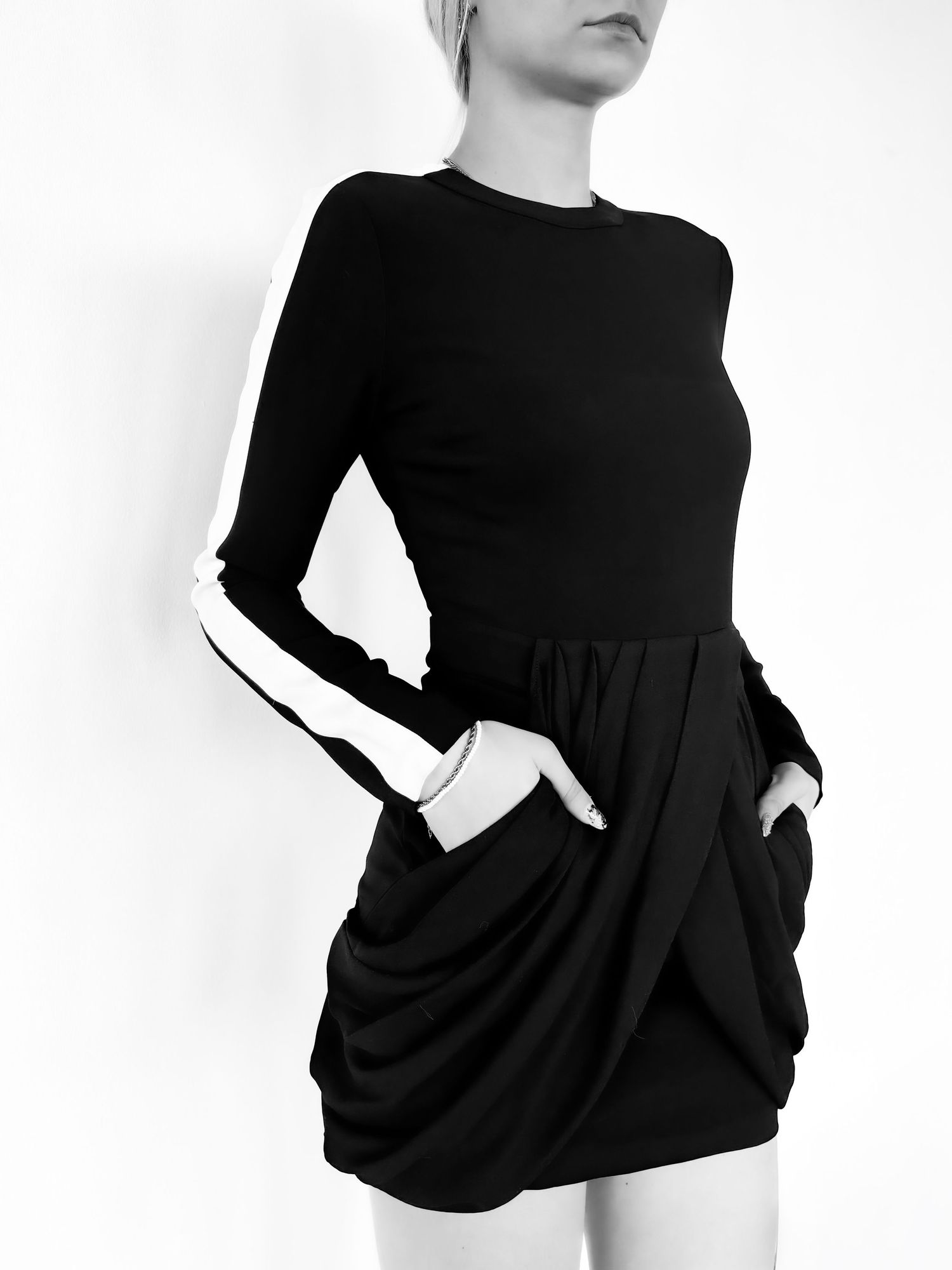 Black long-sleeve mini dress with white contrast stripe on sleeves and draped tulip skirt with pockets.