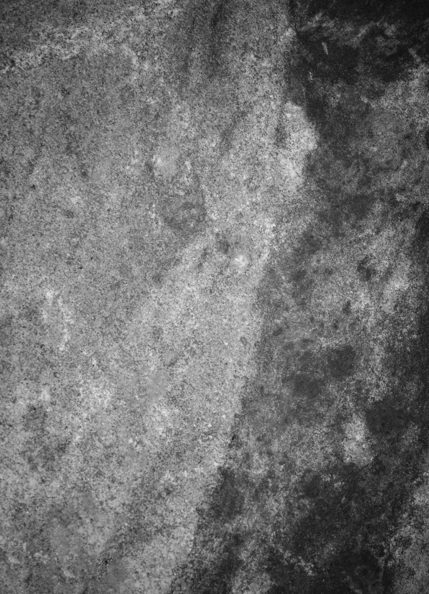 Abstract black and white texture of rough weathered stone surface with natural light and shadow.