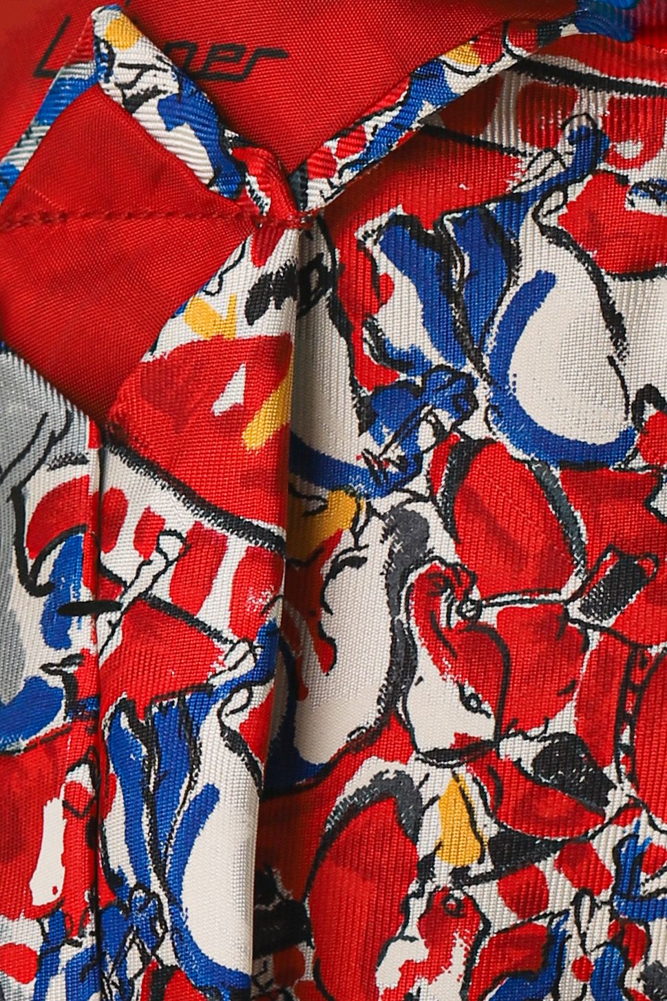 Colorful abstract patterned fabric scarf with red, blue, white, and yellow swirling designs draped elegantly.