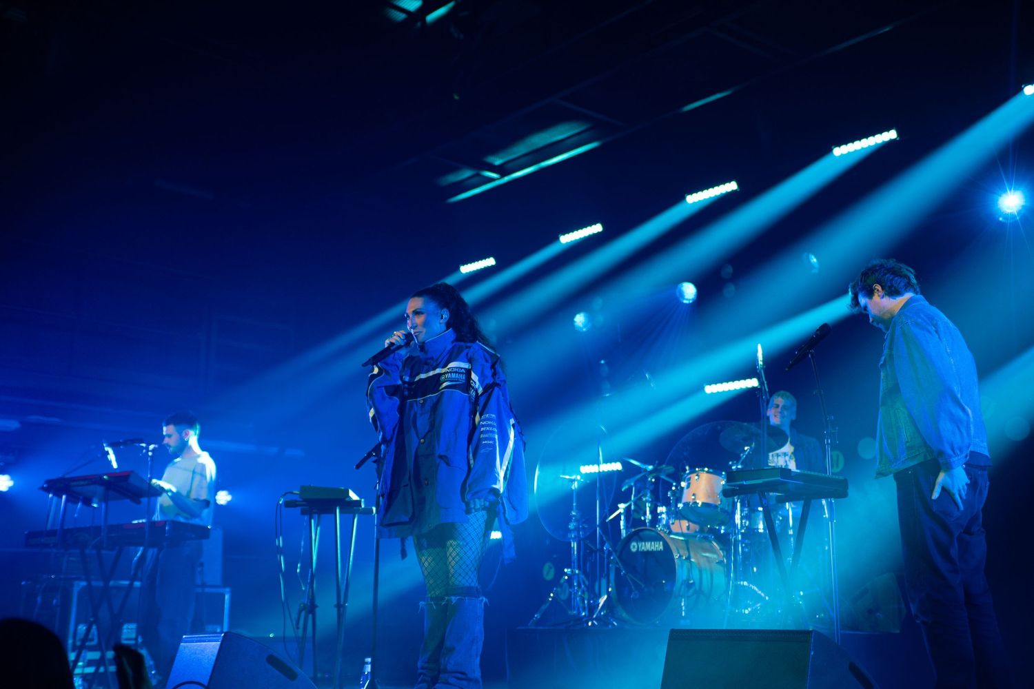 Rock band performing live on stage bathed in dramatic blue stage lighting.
