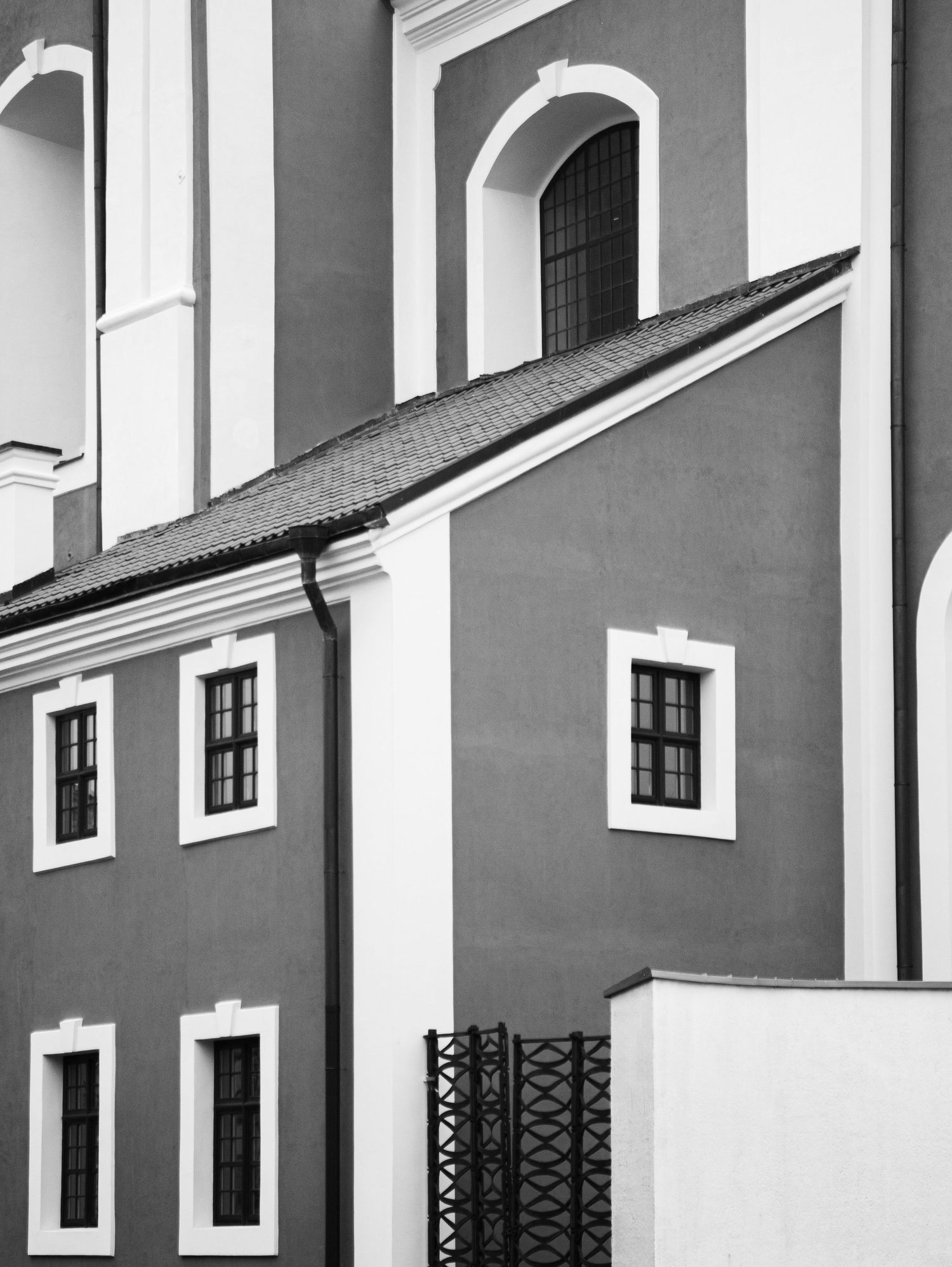 Black and white architectural photo of a historic European building facade with arched windows and white trim.