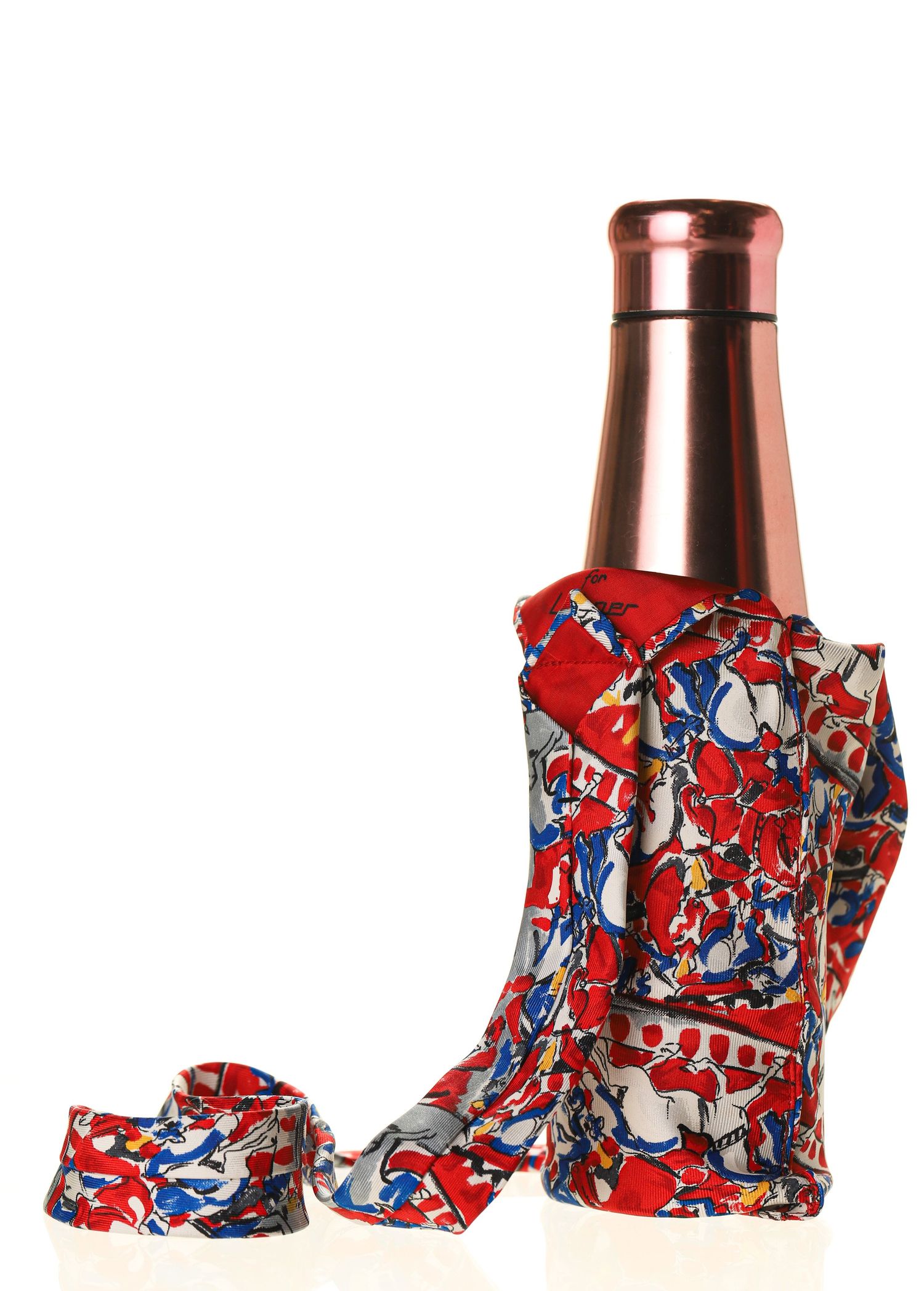 Rose gold bottle wrapped in vibrant red, white, and blue patterned fabric scarf on white background.