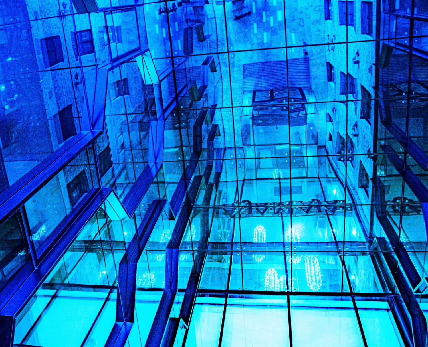 Abstract blue glass architecture with reflective surfaces and geometric patterns creating a stunning modern interior design.
