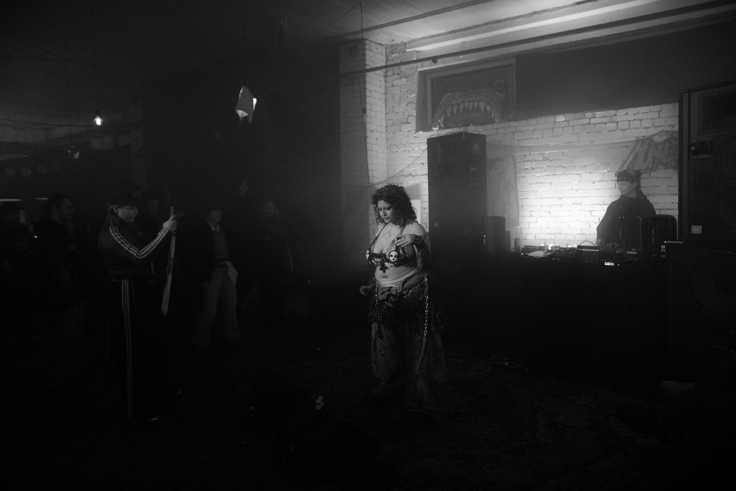 Black and white photo of a performer standing in a smoky dimly lit music venue.