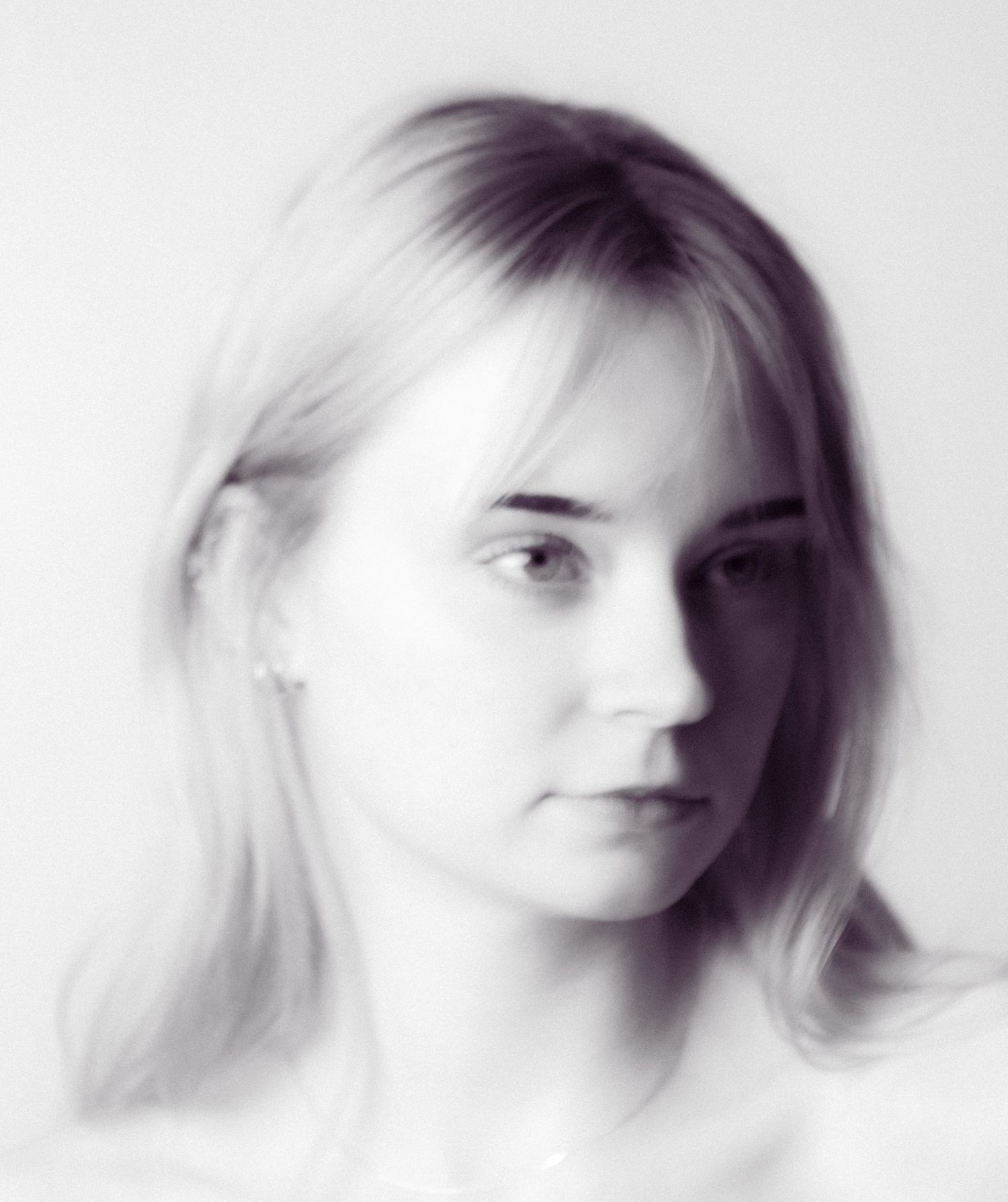 Black and white portrait of a young blonde woman with soft features against a light background.