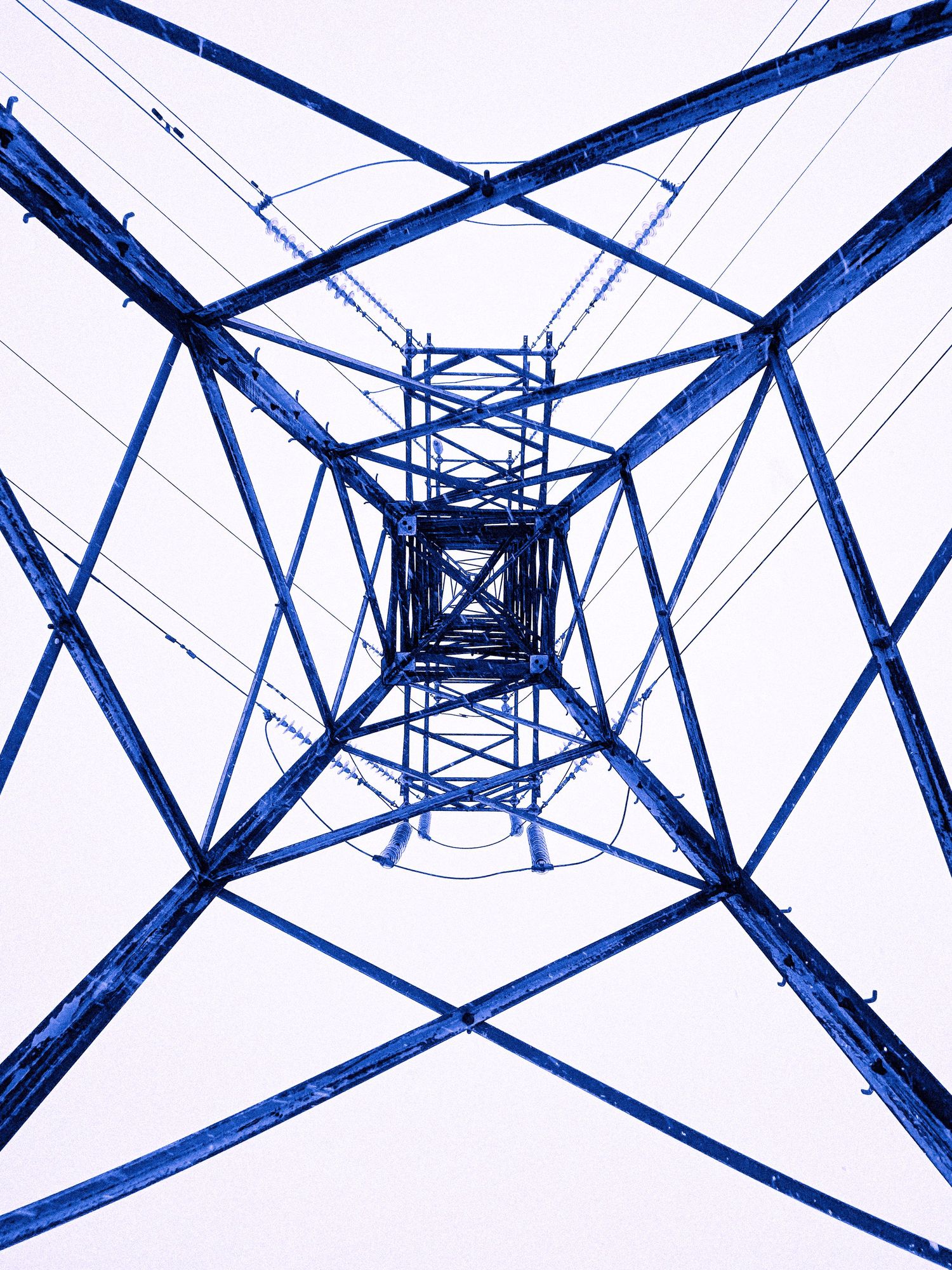 Low angle view looking up through the geometric steel framework of a blue electric power transmission tower.