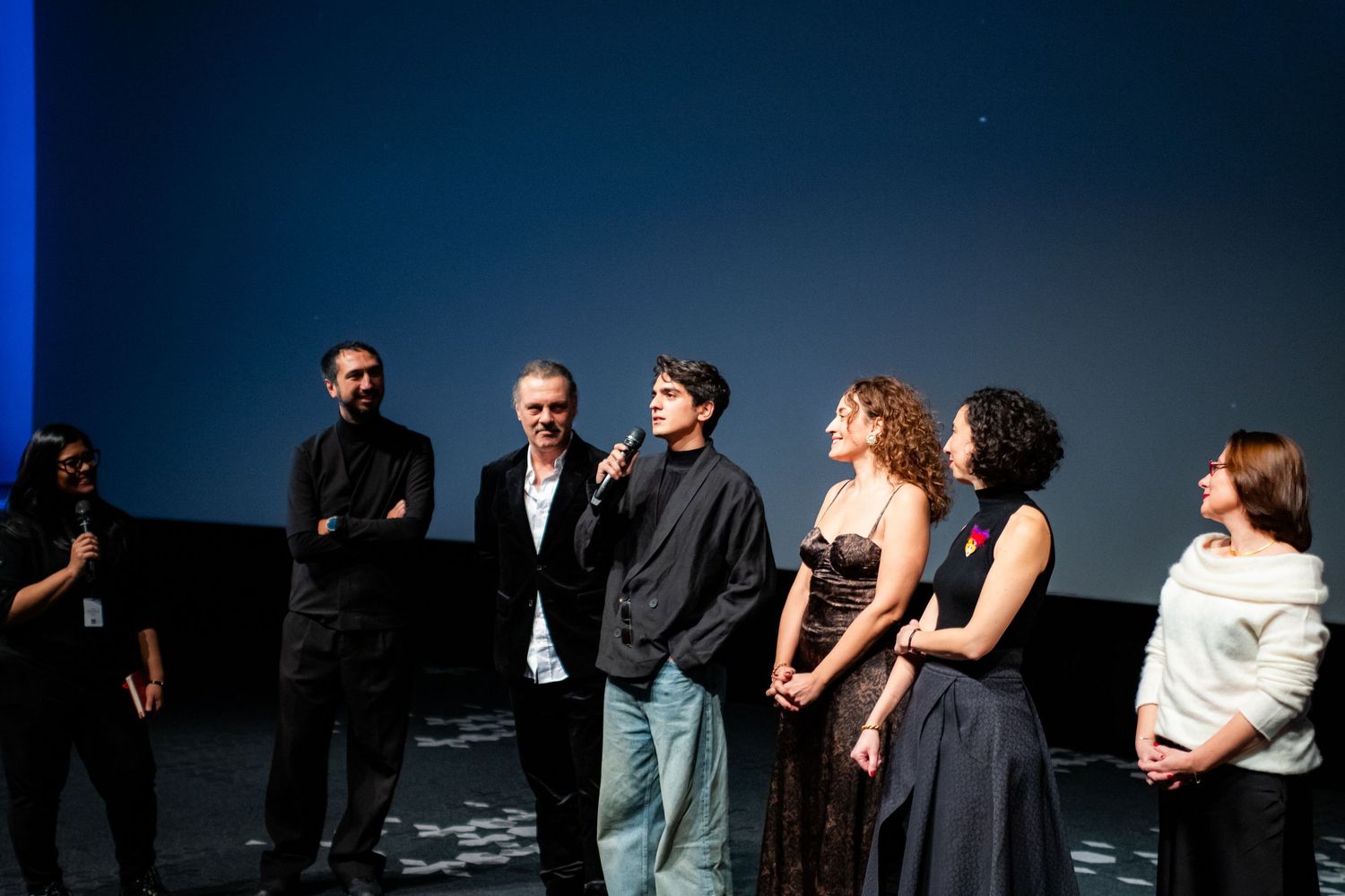 Group of filmmakers and actors speaking on stage at an indoor film festival premiere event.