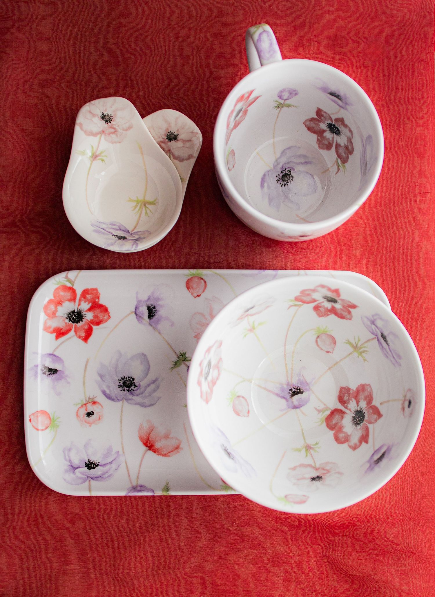 White ceramic dinnerware set with red and purple poppy floral pattern, including tray, bowl, mug, and creamer.