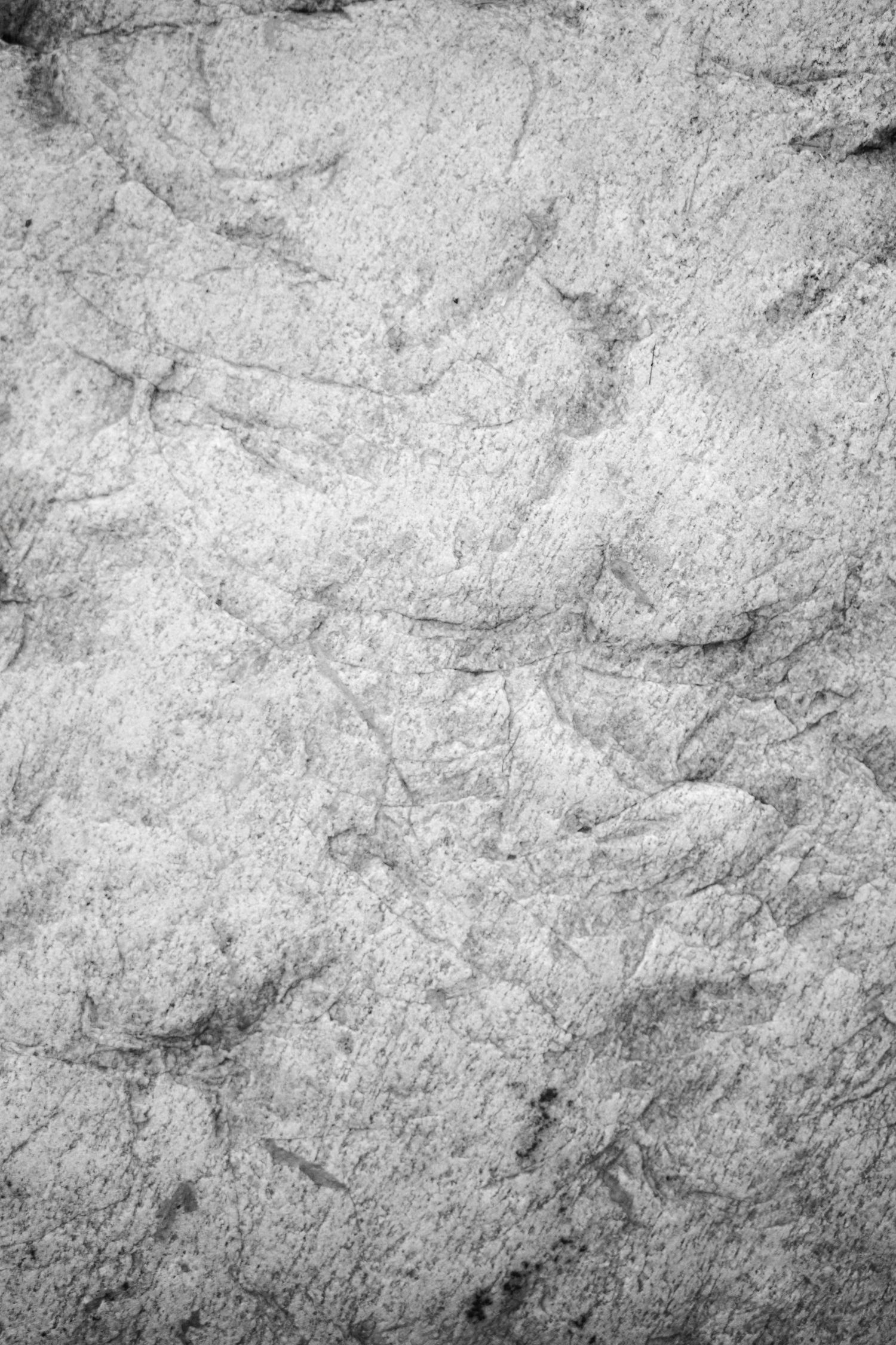 Close-up black and white texture of rough natural stone surface with cracks and grooves.