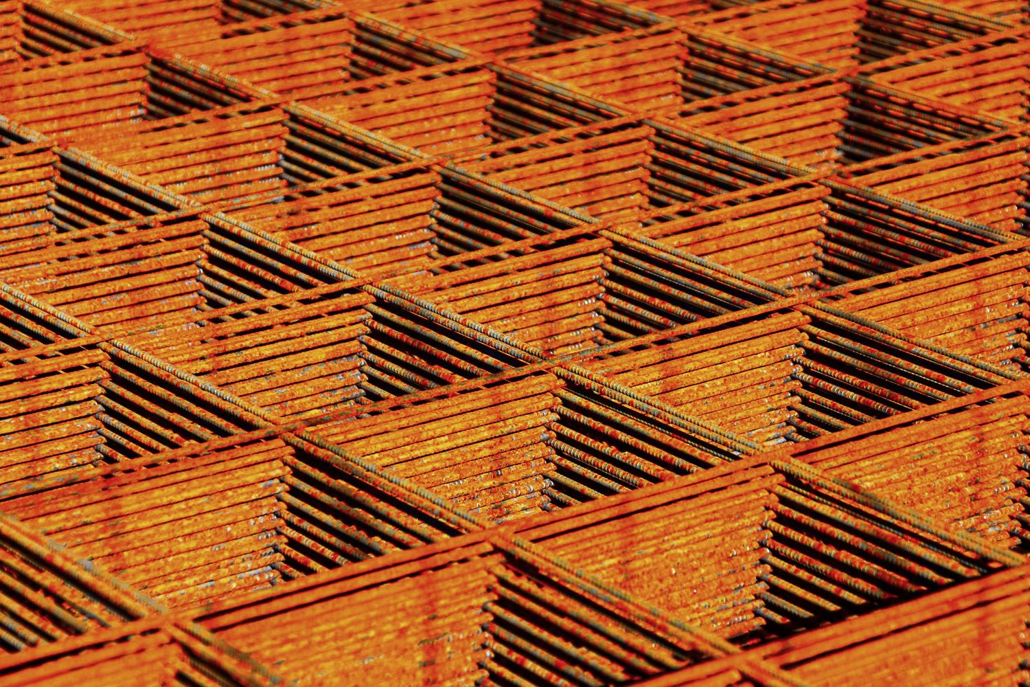 Close-up of rusty orange metal grid mesh with repeating geometric square pattern texture.