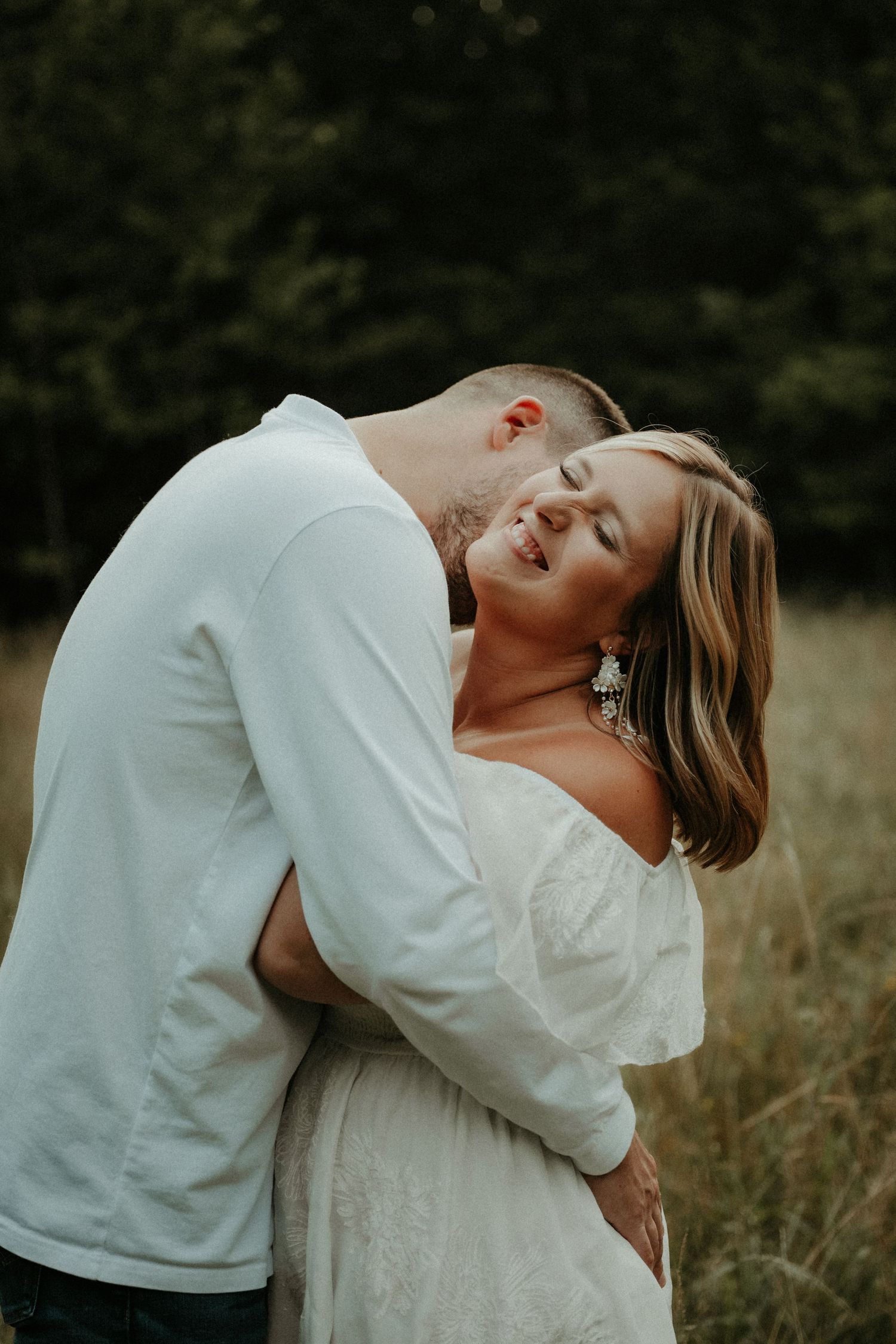 Intimate outdoor portrait of a couple embracing in a field during golden hour, wearing white outfits. Pittsburgh Wedding Photographer