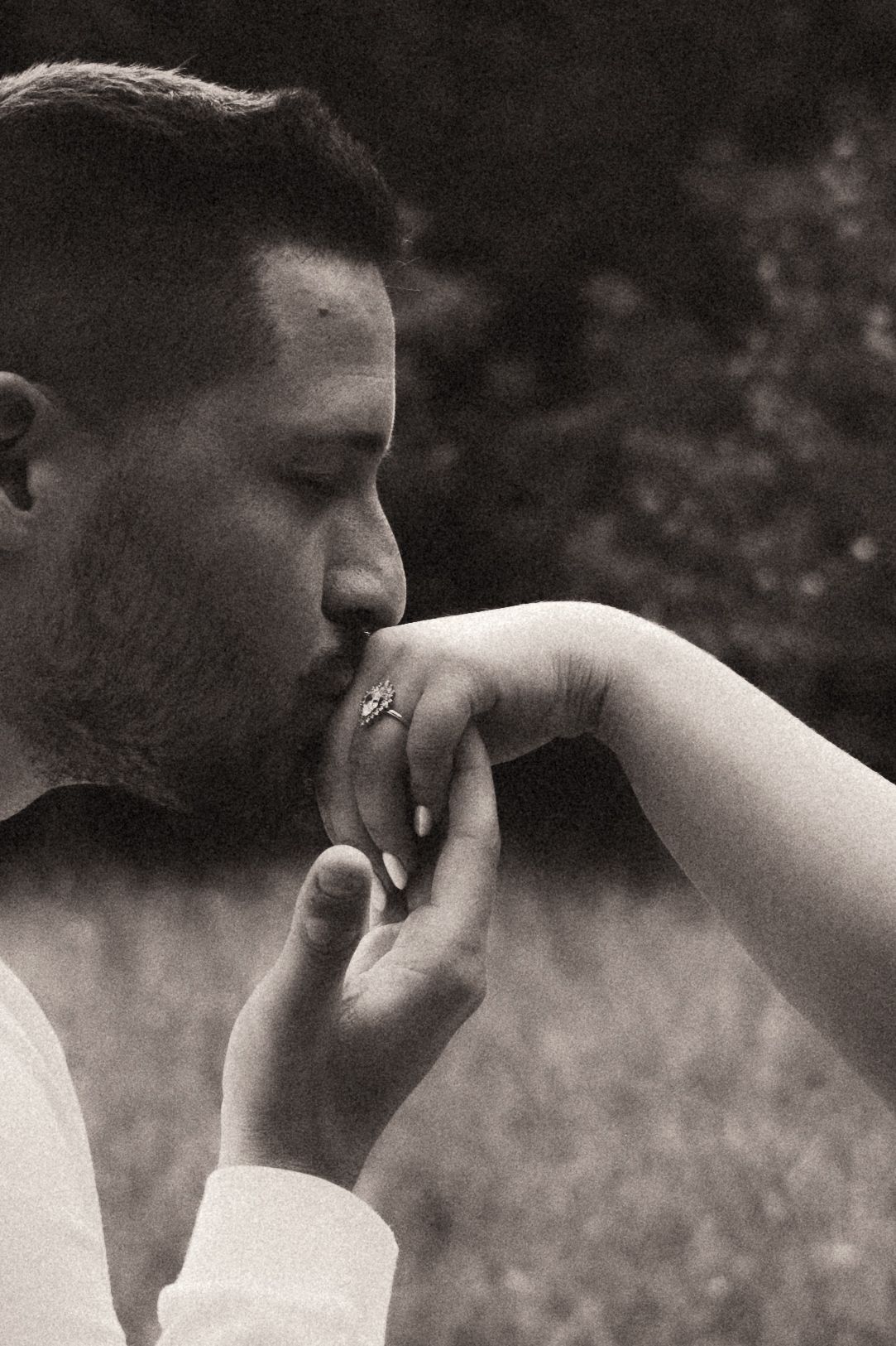 A black and white photograph capturing an intimate moment as someone gently kisses another's hand outdoors. Pittsburgh Wedding Photographer