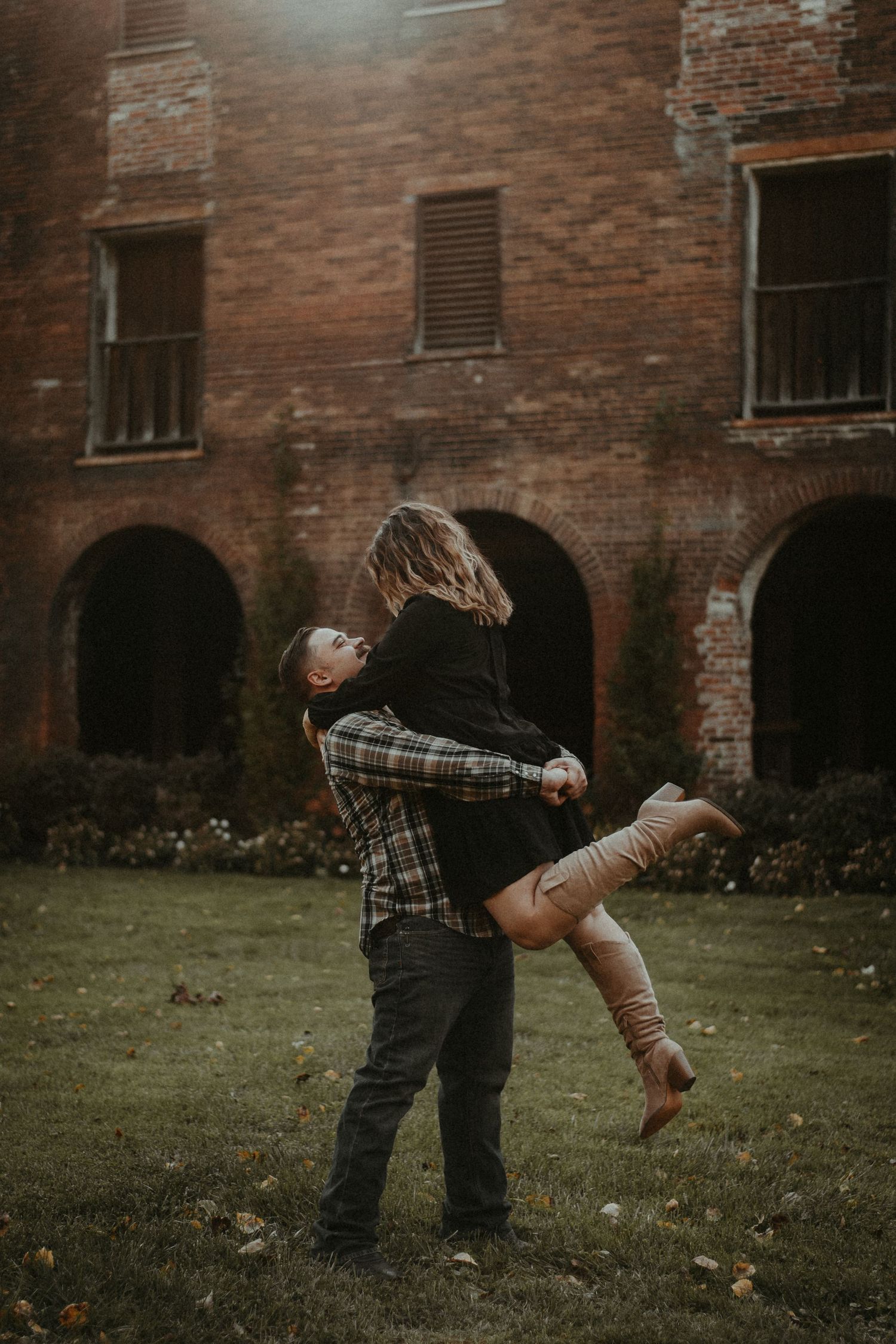Romantic embrace in front of rustic brick building with arched windows. Pittsburgh Wedding Photographer