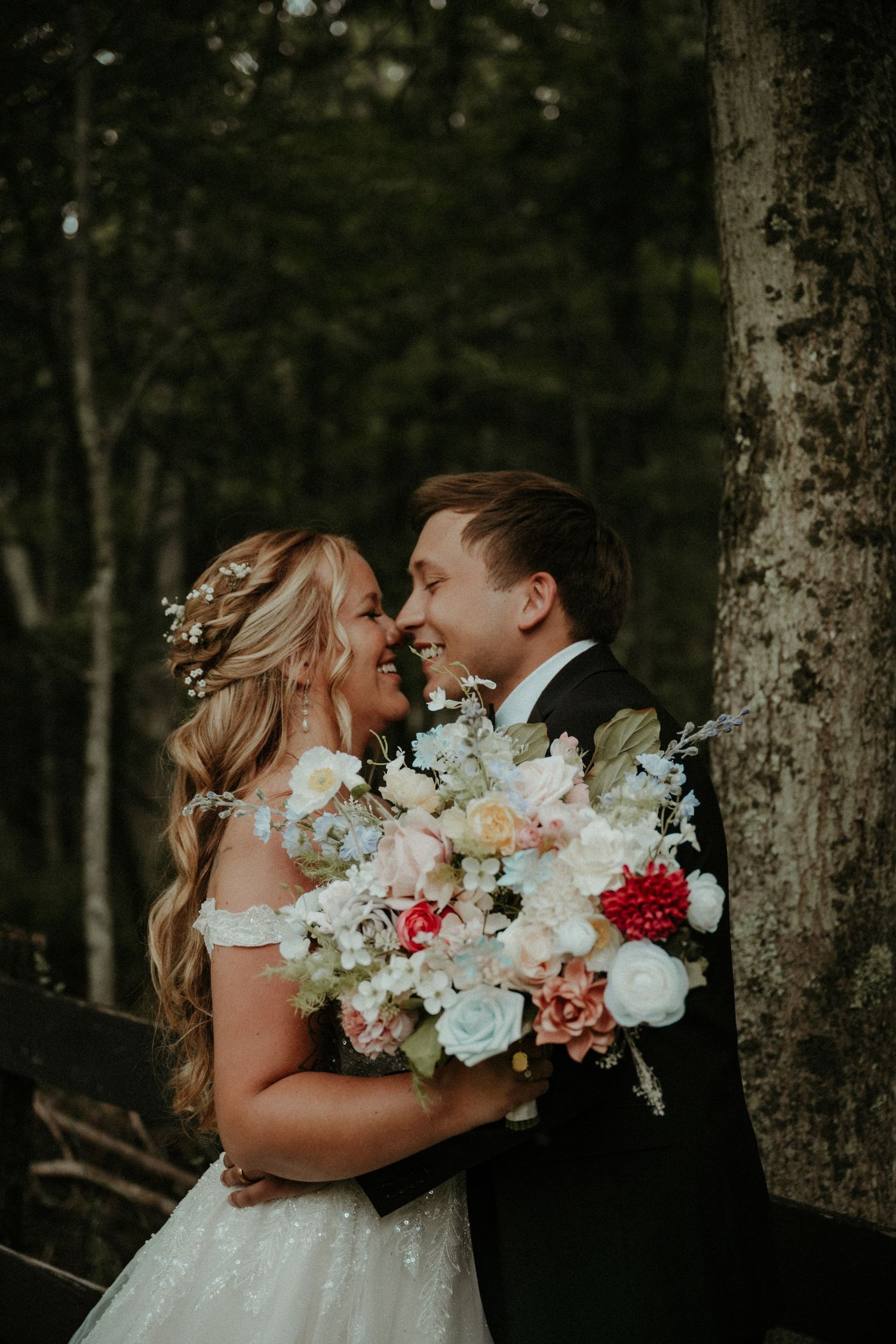 Romantic couple share intimate moment in a forest setting with stunning floral bouquet. Pittsburgh Wedding Photographer