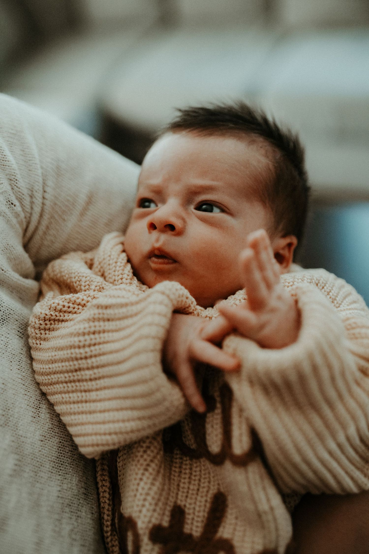 Close-up of baby in knit sweater making expressive face.