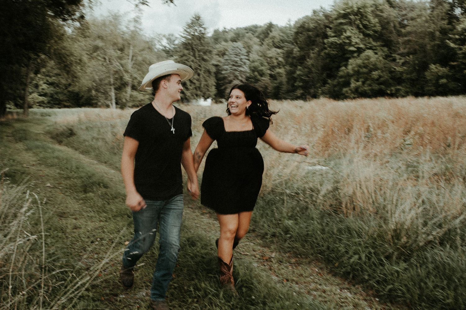 Couple walking and laughing together on rural path through tall grass. Pittsburgh Wedding Photographer