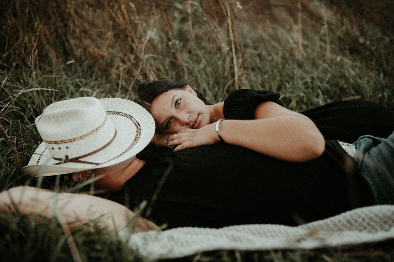 A relaxed moment captured of someone resting on a blanket with a hat in tall grass. Pittsburgh Wedding Photographer