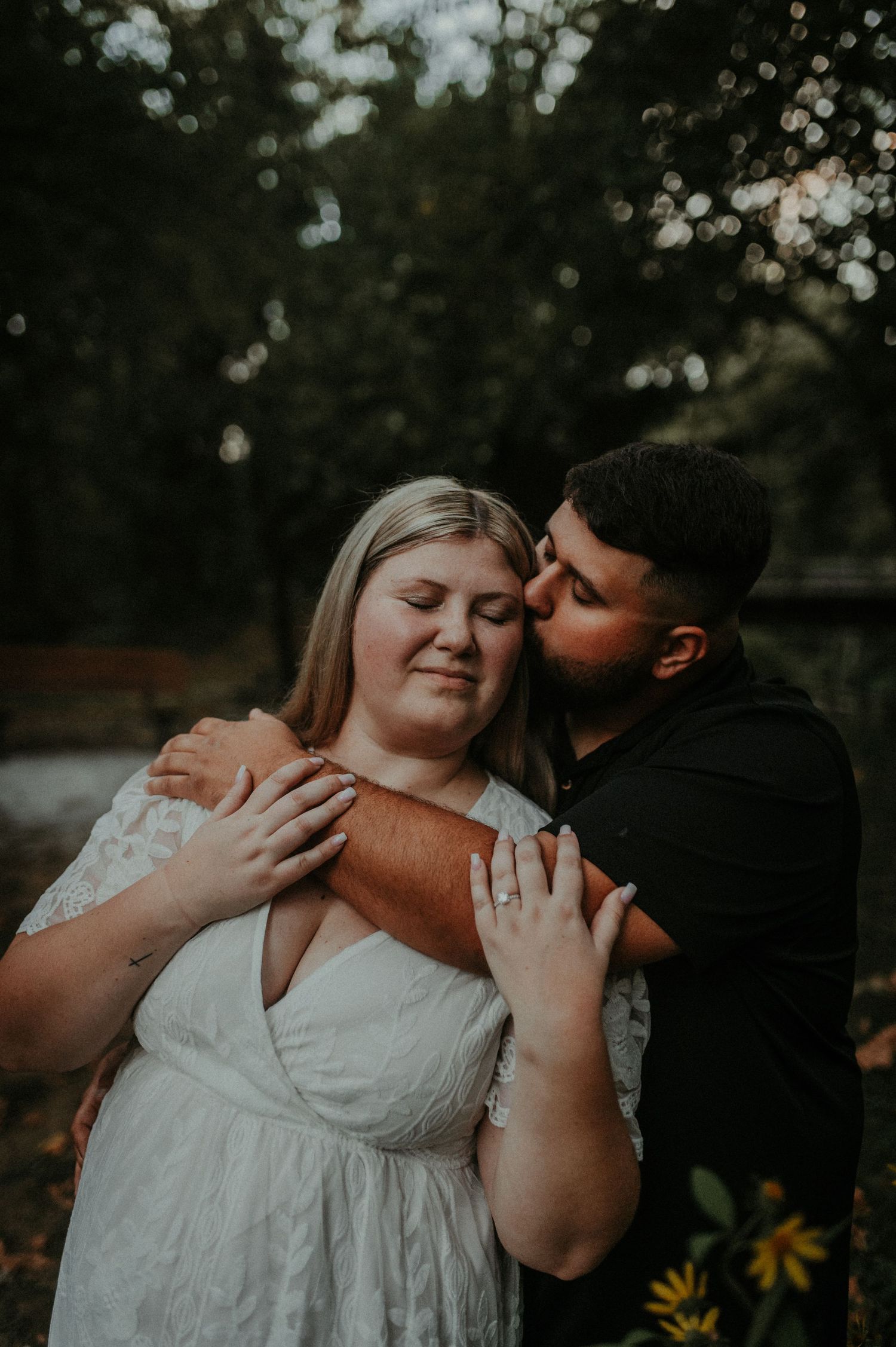 A romantic couple in an outdoor setting with soft lighting embraces tenderly during their photo session. Pittsburgh Wedding Photographer