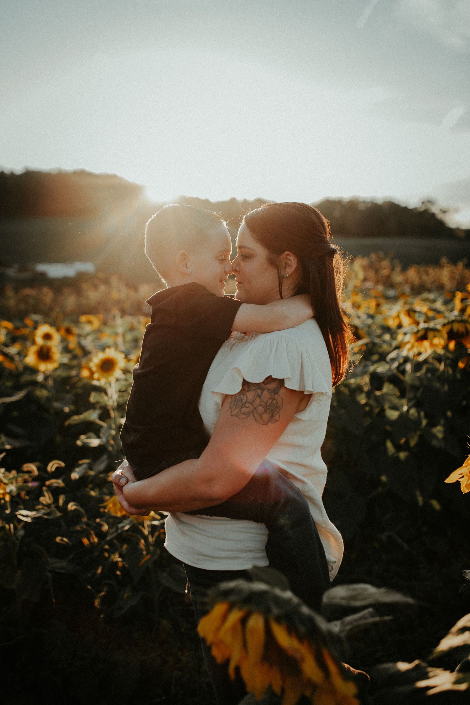 Intimate embrace in sunflower field during golden hour sunset.