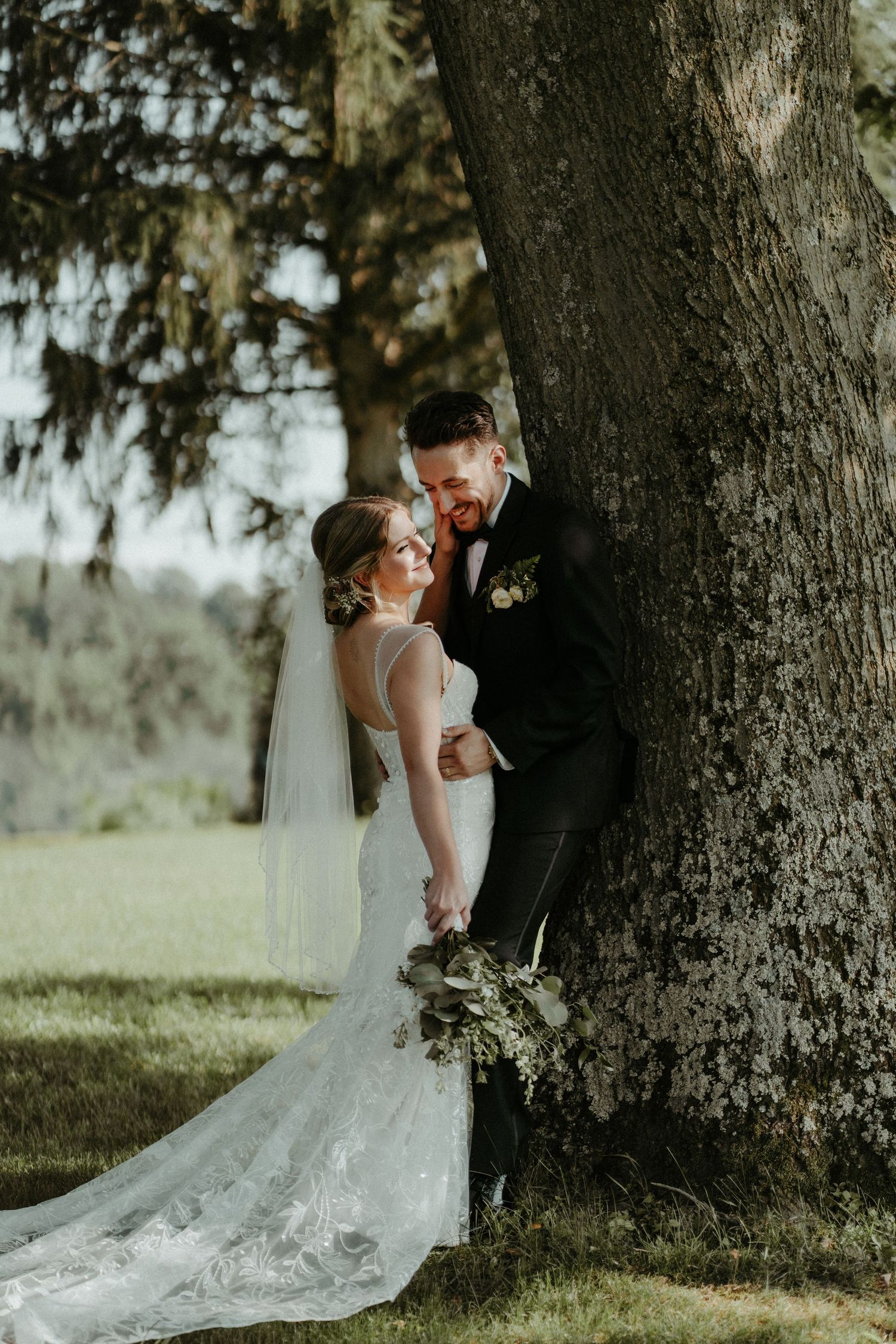 A newlywed couple embraces under a large tree during their outdoor wedding photoshoot at golden hour. Pittsburgh Wedding Photographer