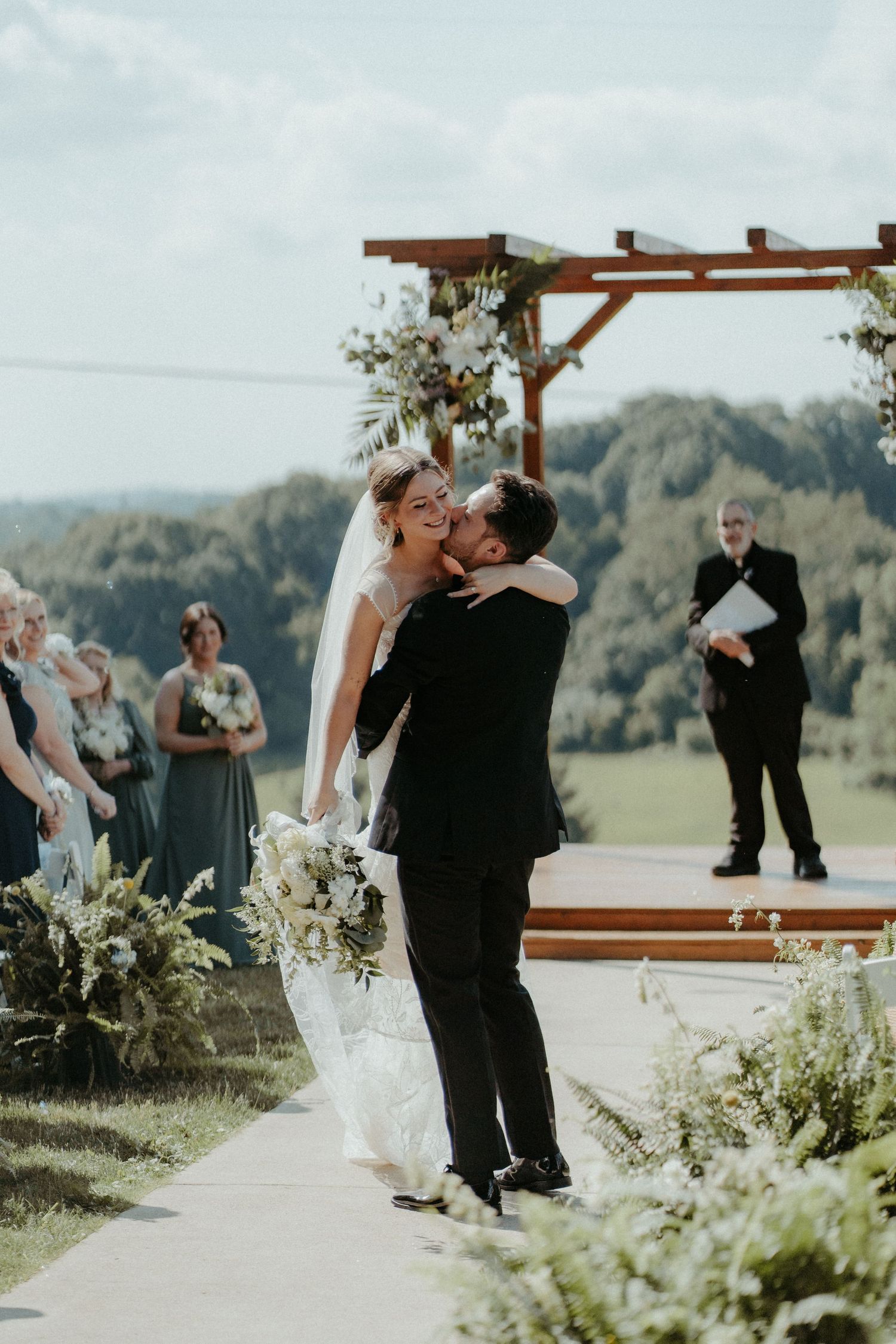 A romantic wedding ceremony unfolds under a rustic wooden arch with mountain views in the background. Pittsburgh Wedding Photographer