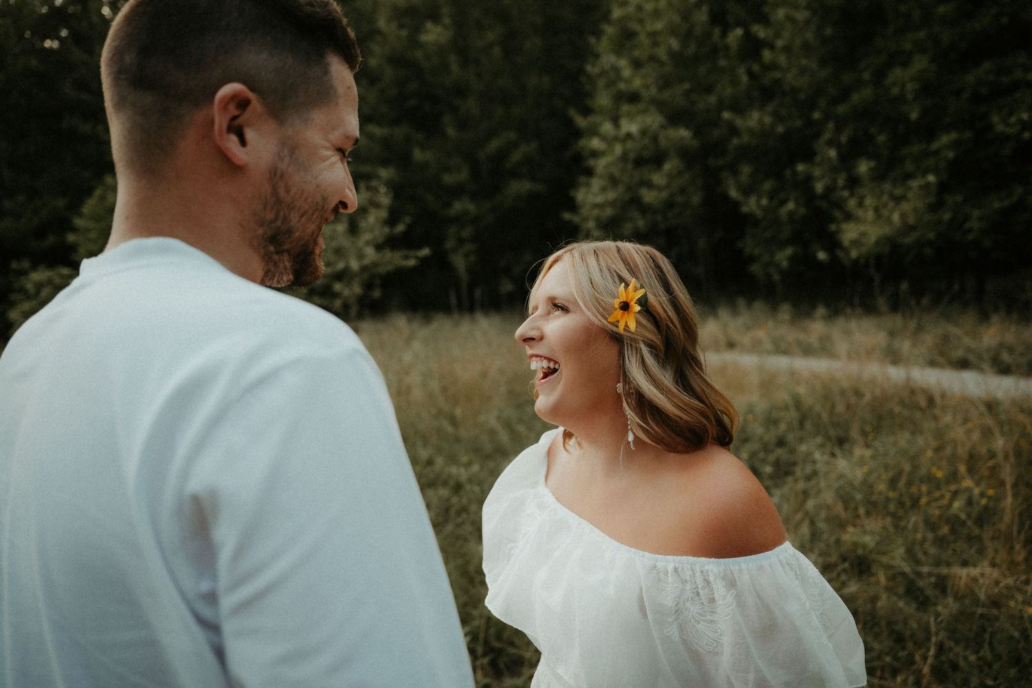 A romantic outdoor couple's photo shows them sharing a joyful moment in a sunlit meadow, dressed in white. Pittsburgh Wedding Photographer