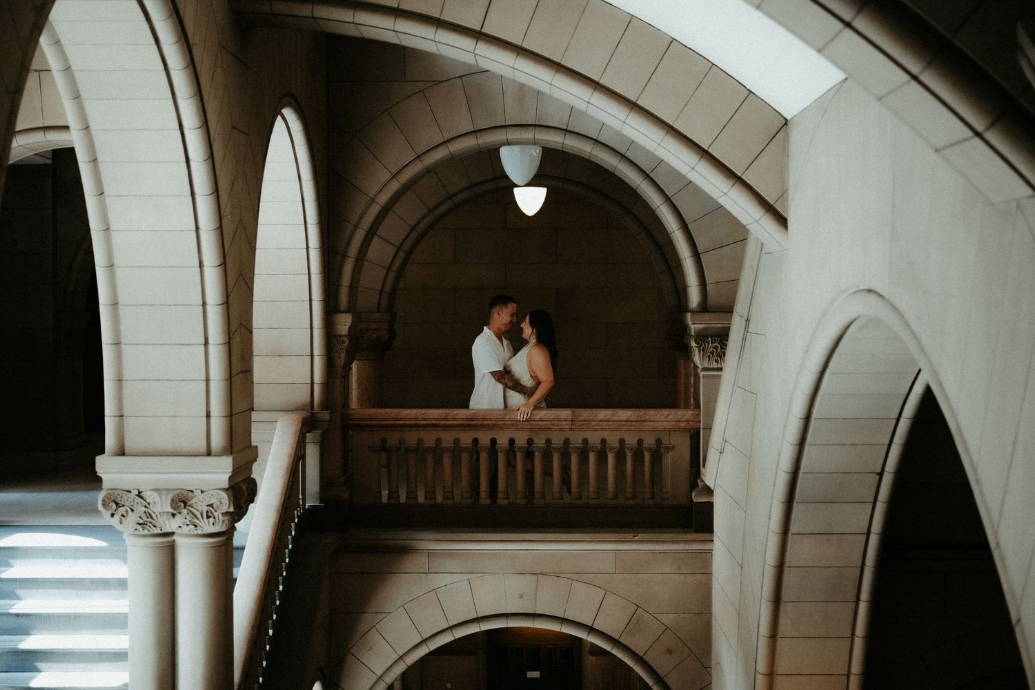 An elegant wedding couple shares an intimate moment under stone archways in a historic building interior. Pittsburgh Wedding Photographer