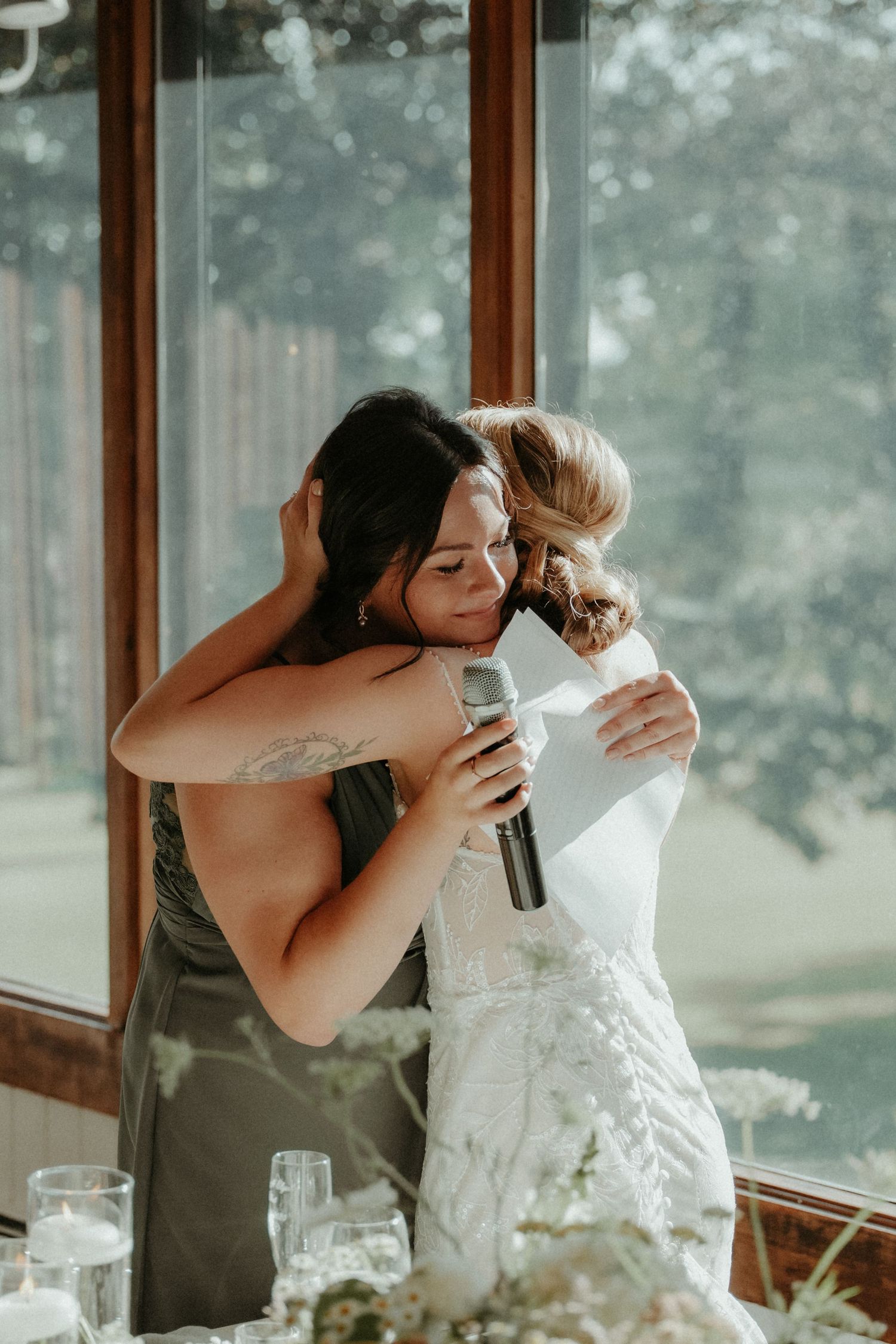 Two people share an emotional embrace during what appears to be a wedding ceremony in a sunlit room.