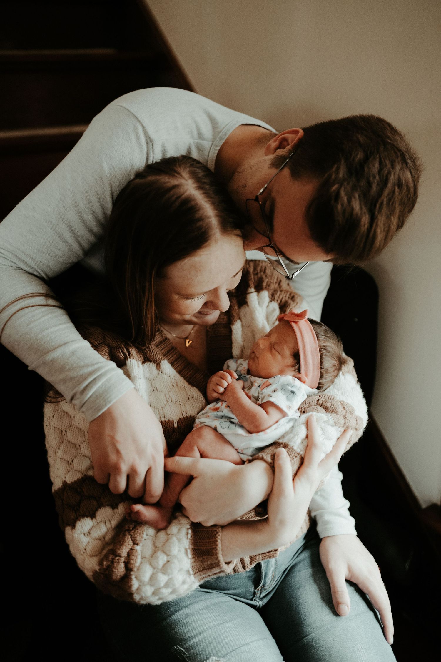 Tender family moment with newborn baby in intimate indoor setting.