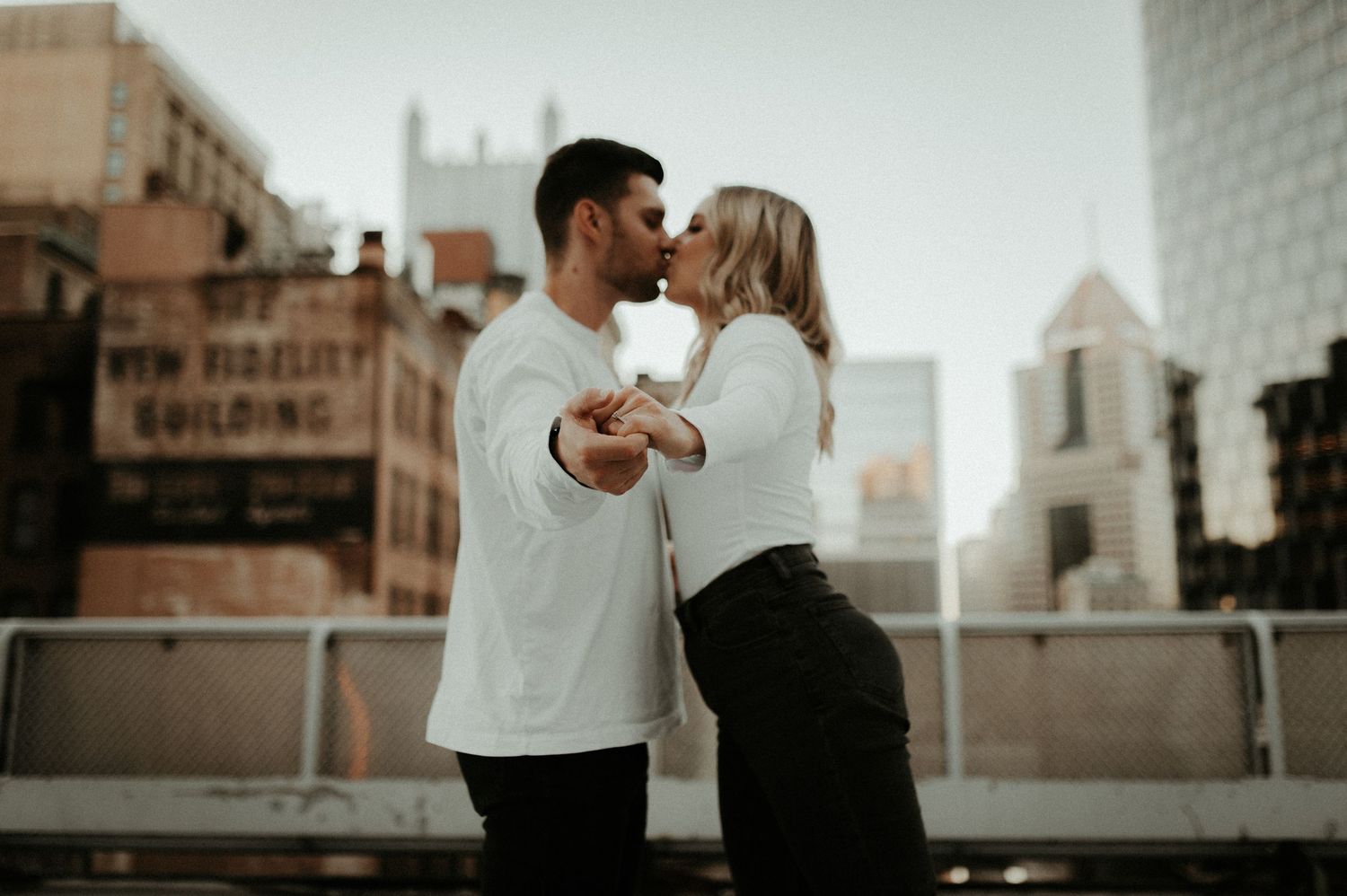 A romantic couple dancing together on a rooftop with urban city buildings in the background at dusk. Pittsburgh Wedding Photographer