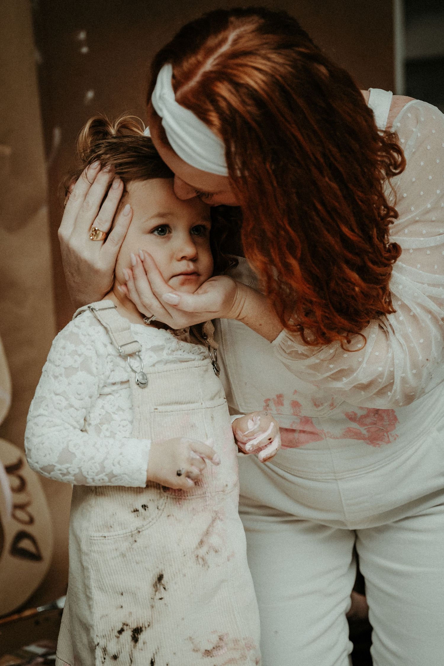 A tender moment between parent and child both wearing white lace.