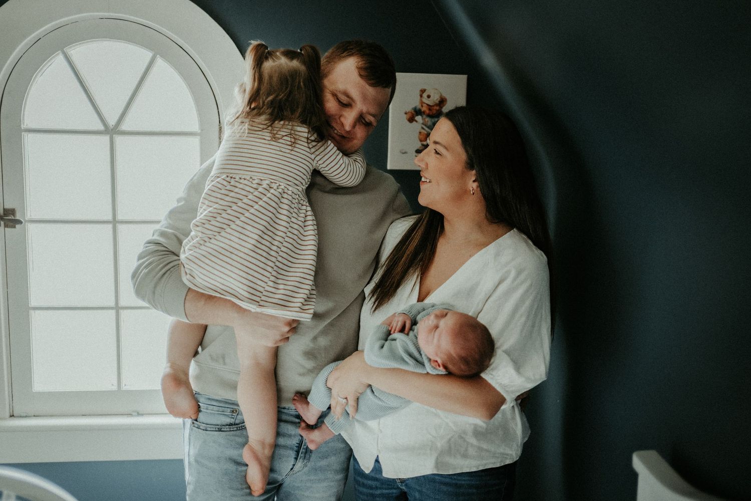 A family shares intimate moments while posing together in front of a white window. Pittsburgh / Westmoreland Photographer