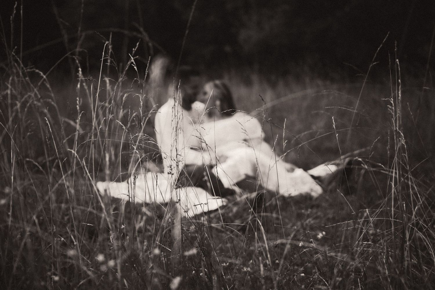 Black and white photographs showing couples lying in grass fields creating a romantic montage effect. Pittsburgh Wedding Photographer
