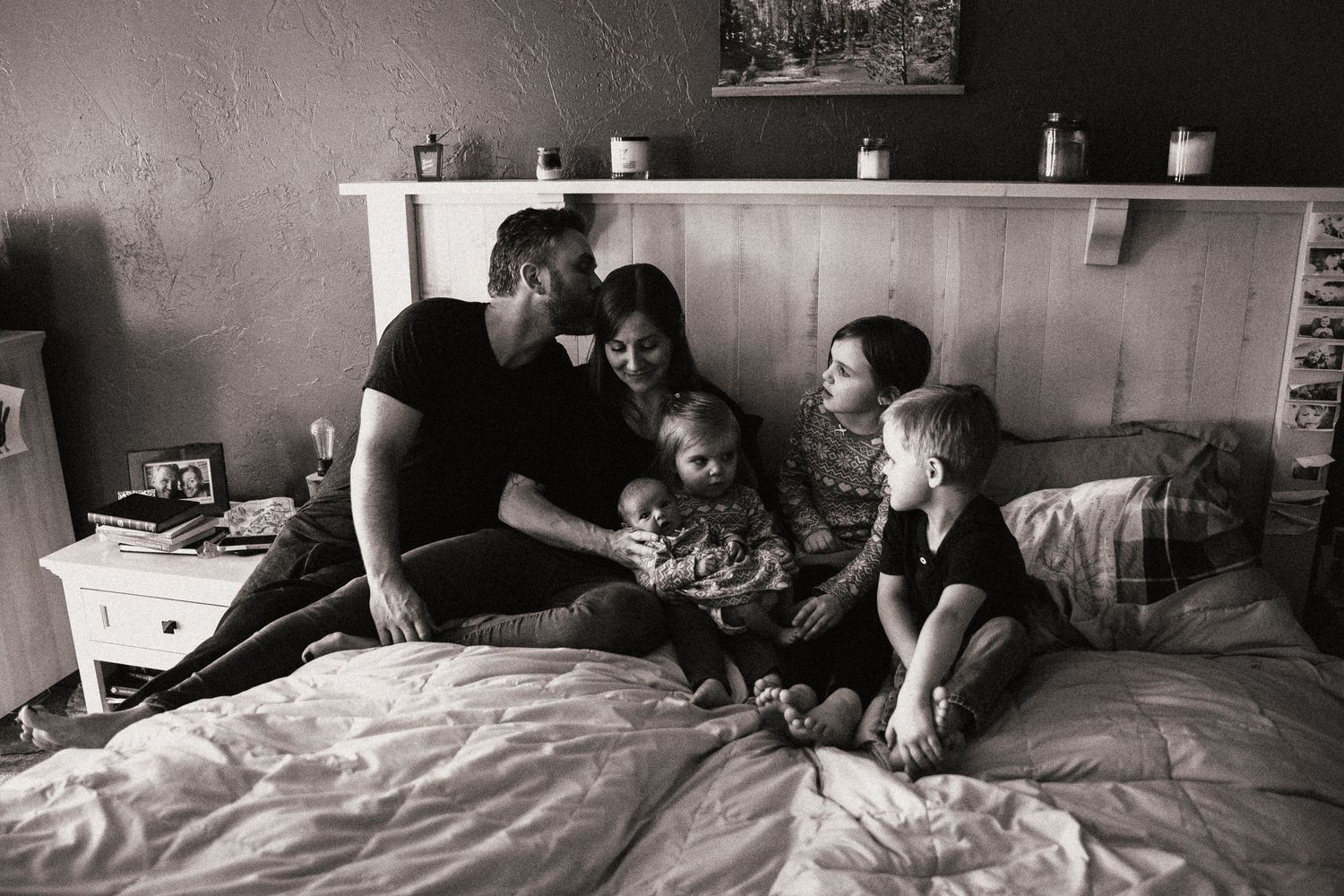 A tender family moment shared on a bed in black and white photography.