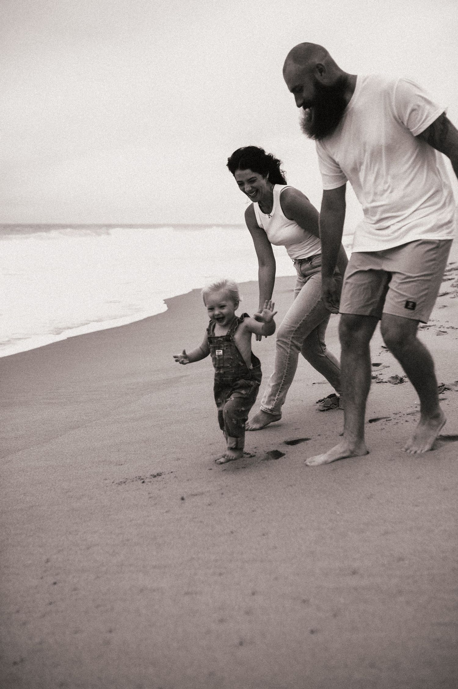 Family enjoying a beach walk together on a cloudy day.