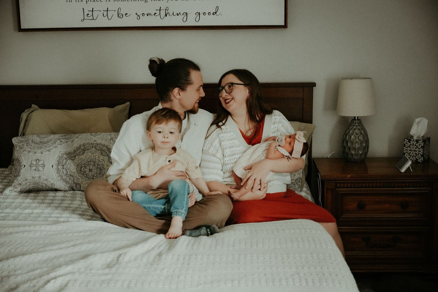 A family lies comfortably together on a white bed while sharing tender moments and laughter. Pittsburgh / Westmoreland Photographer
